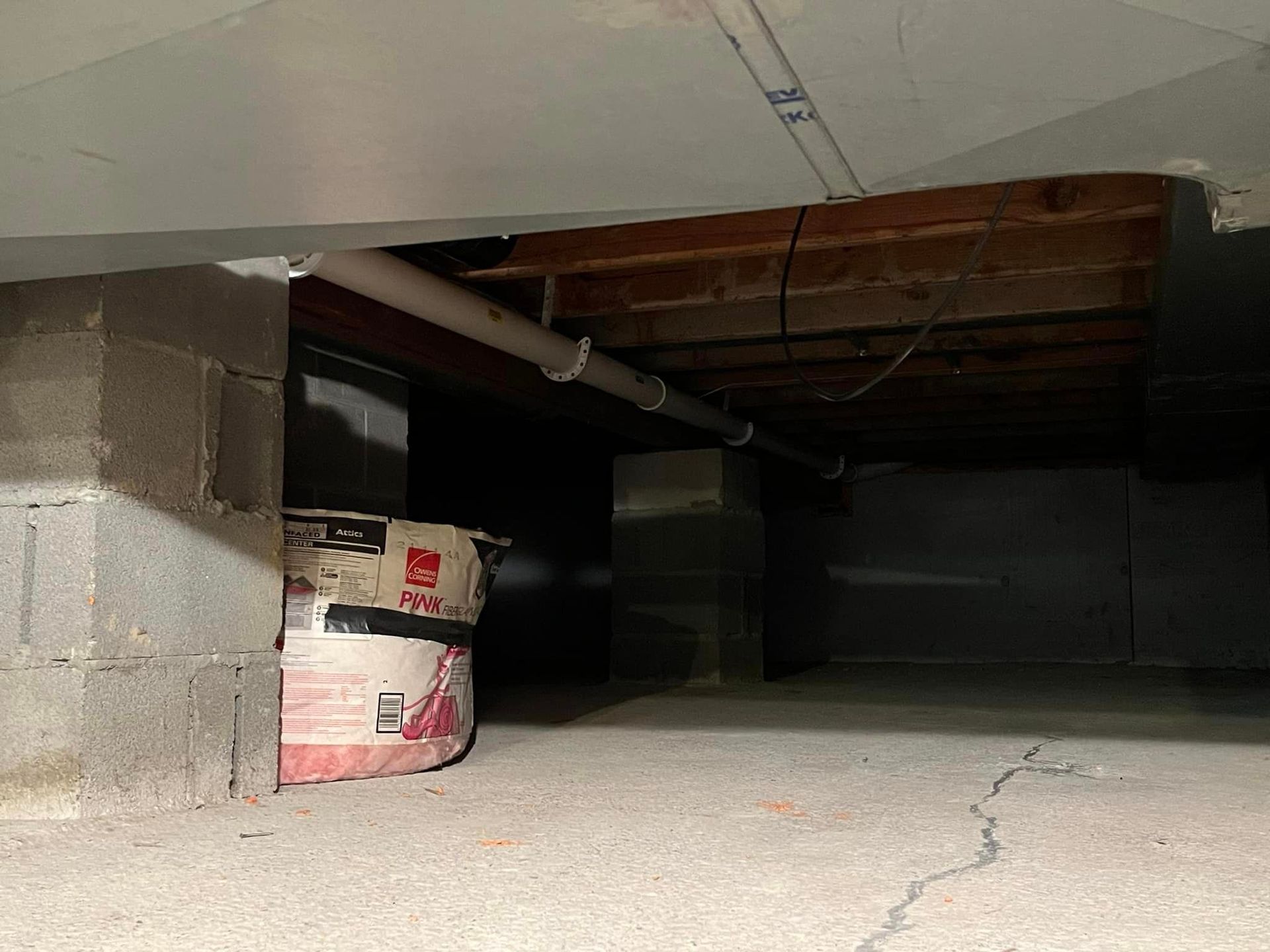 A basement with a vacuum cleaner and a bucket of paint.