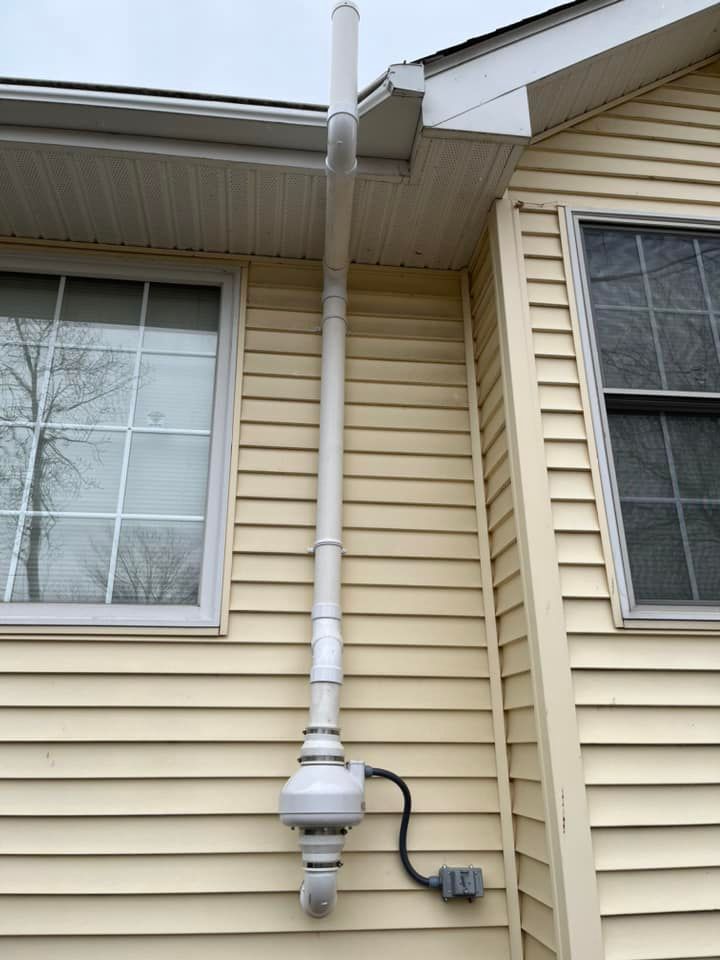 A white pipe is attached to the side of a house.