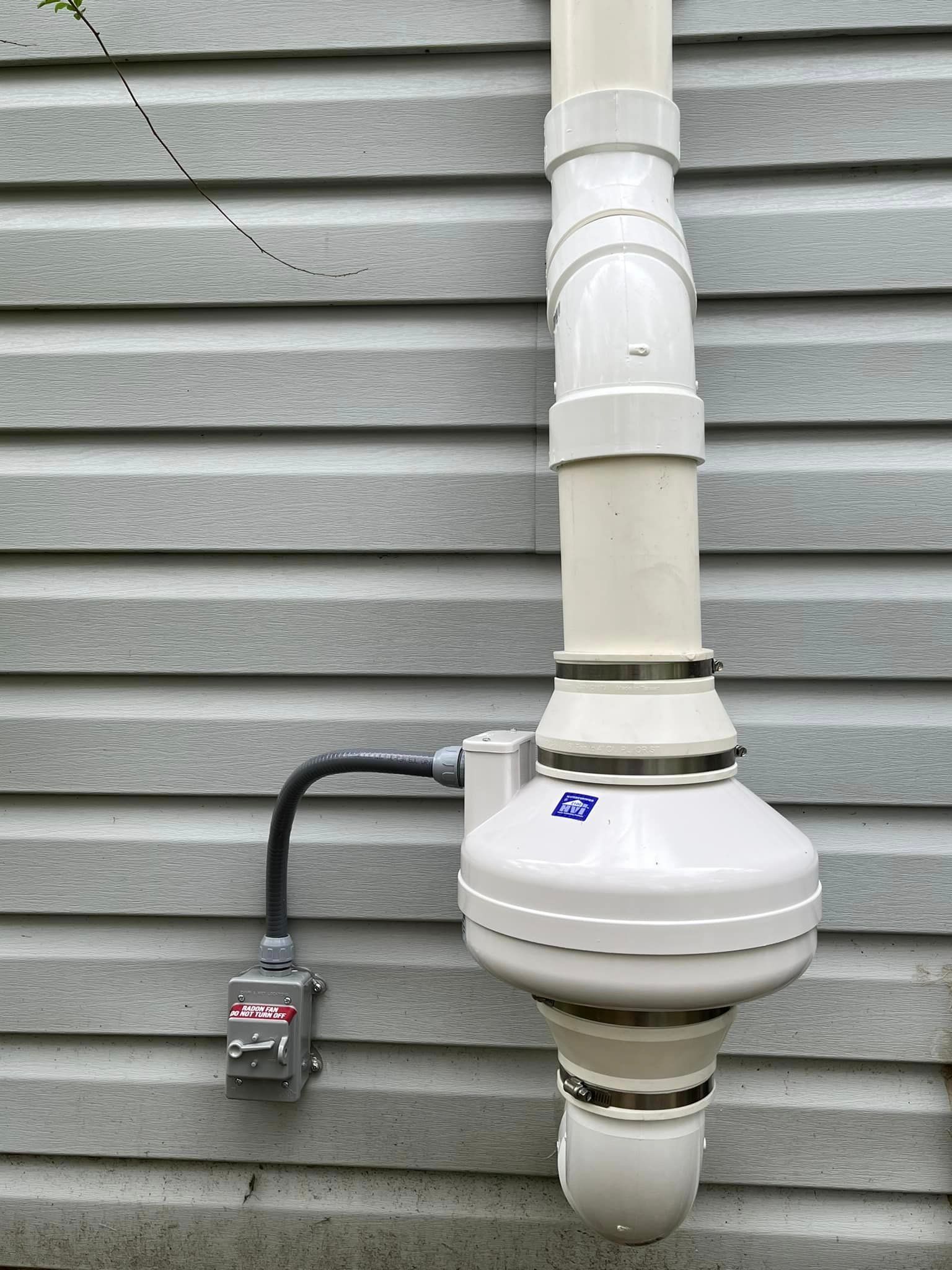 A white pipe is attached to the side of a house.