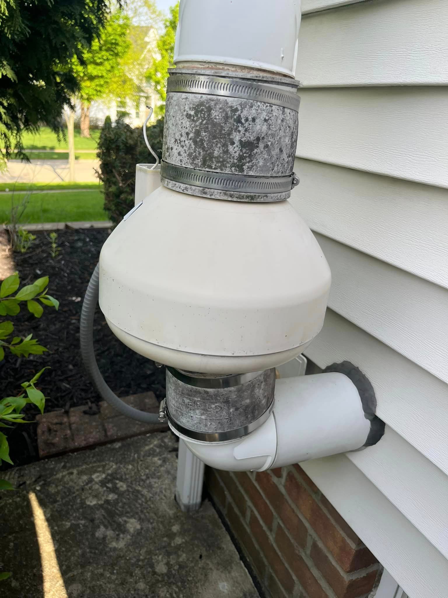 A white pipe is attached to the side of a house.
