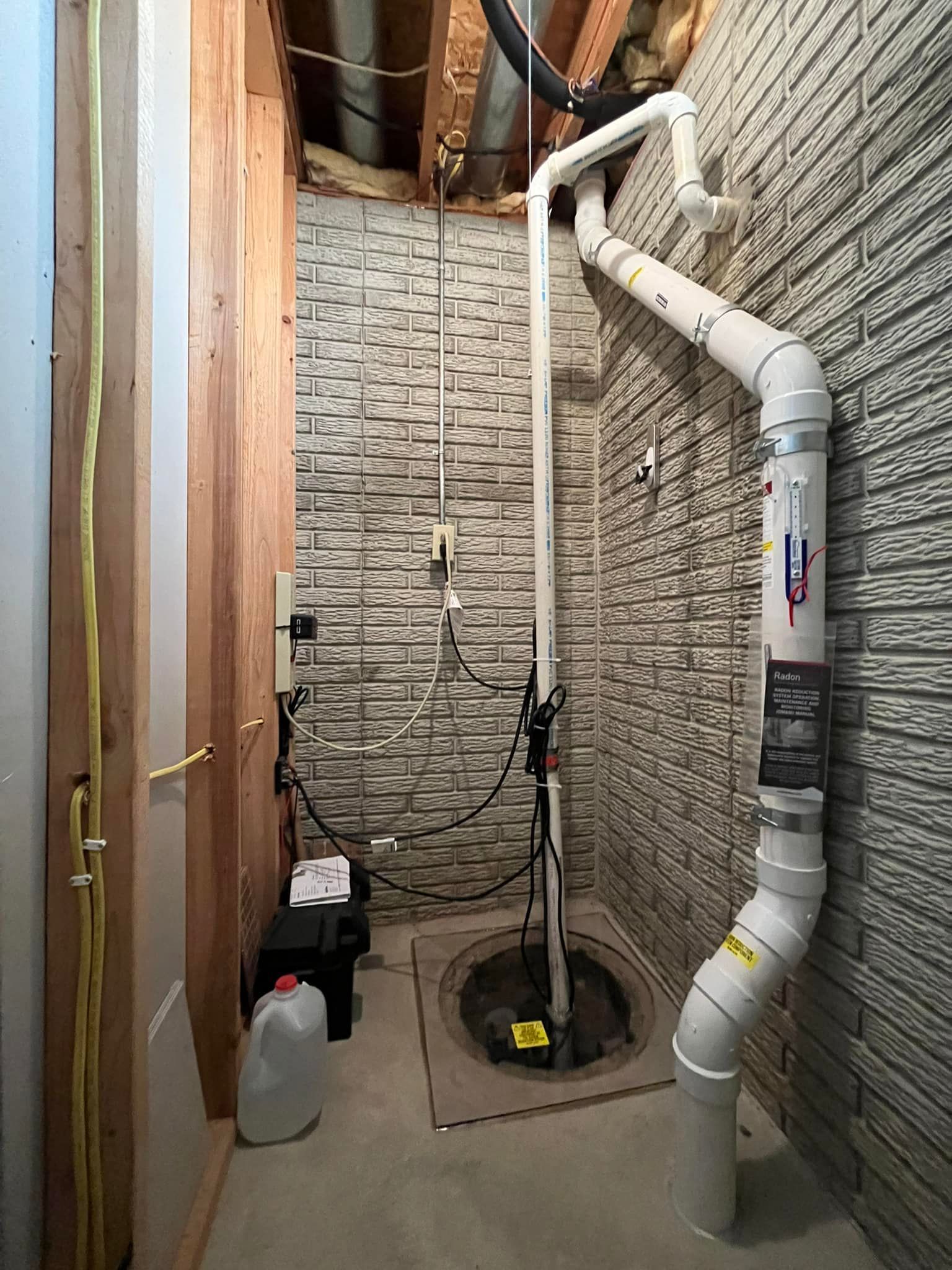 A basement with a brick wall and a drain pipe coming out of it.