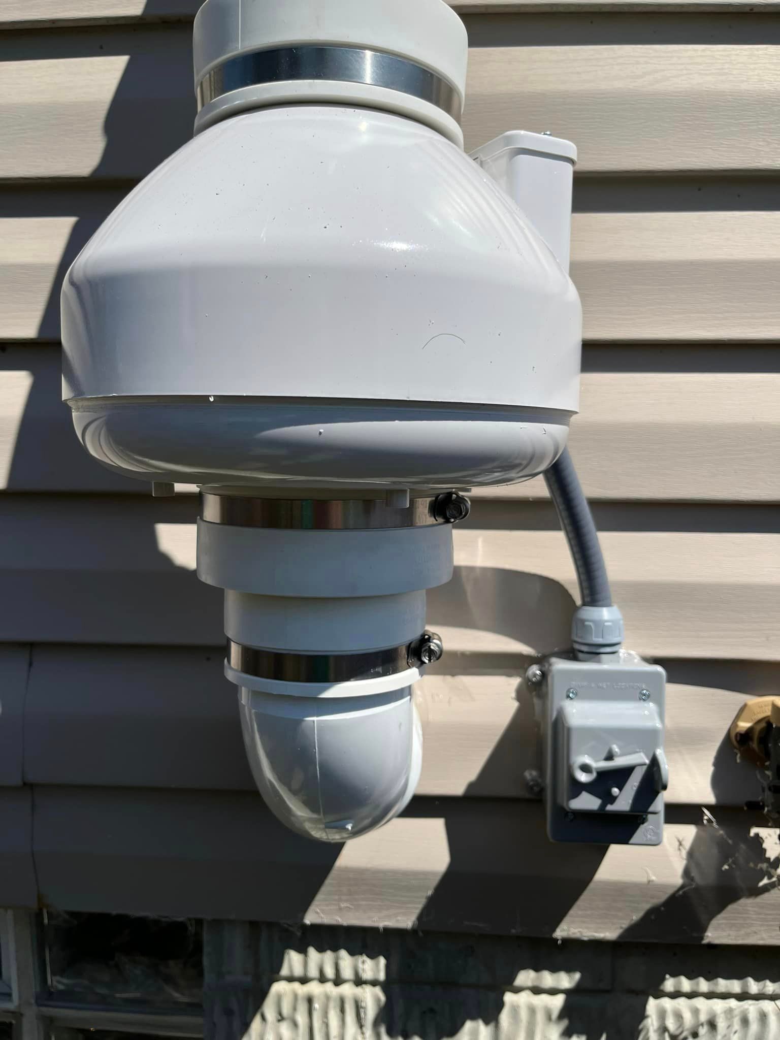A white pipe is attached to the side of a house.