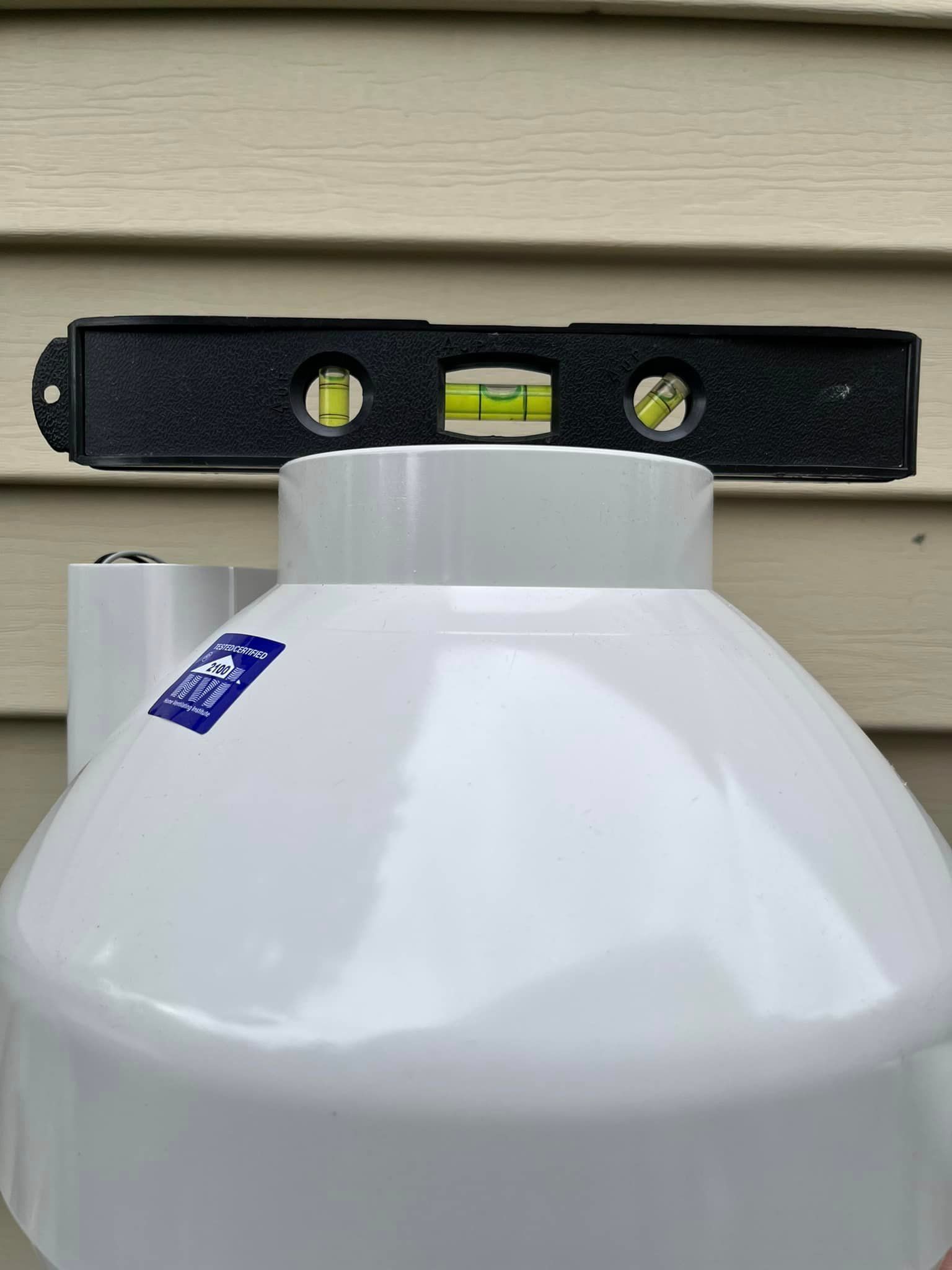 A level is sitting on top of a white propane tank.