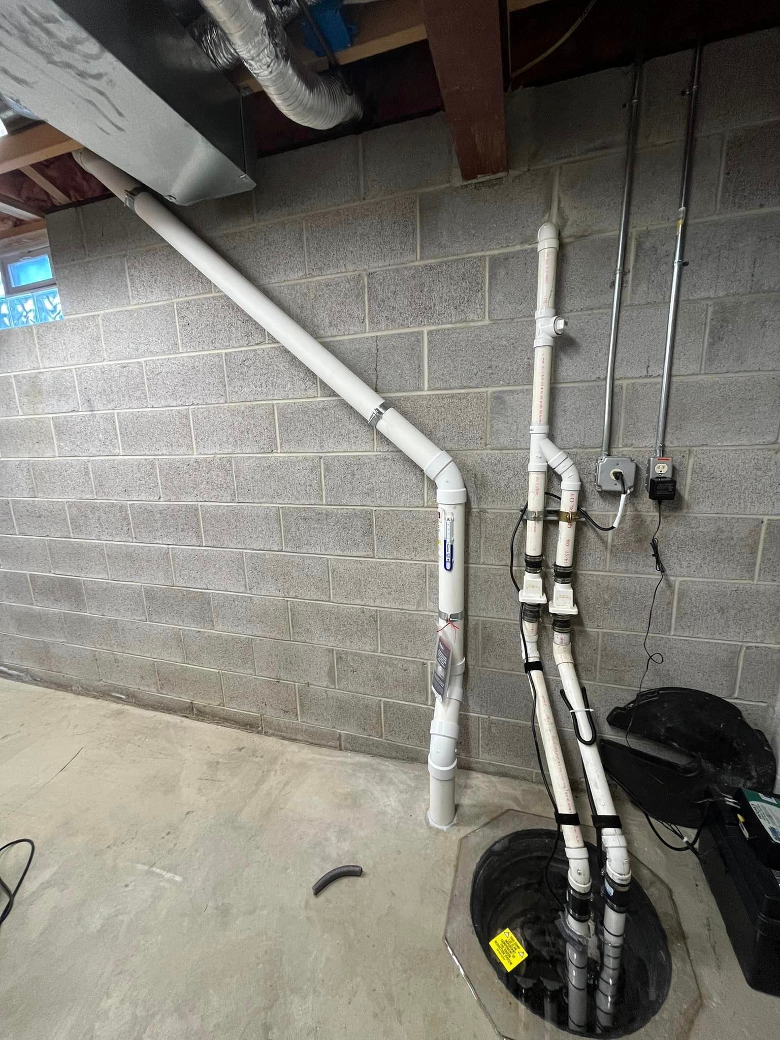 A bunch of pipes are connected to a sump in a basement.