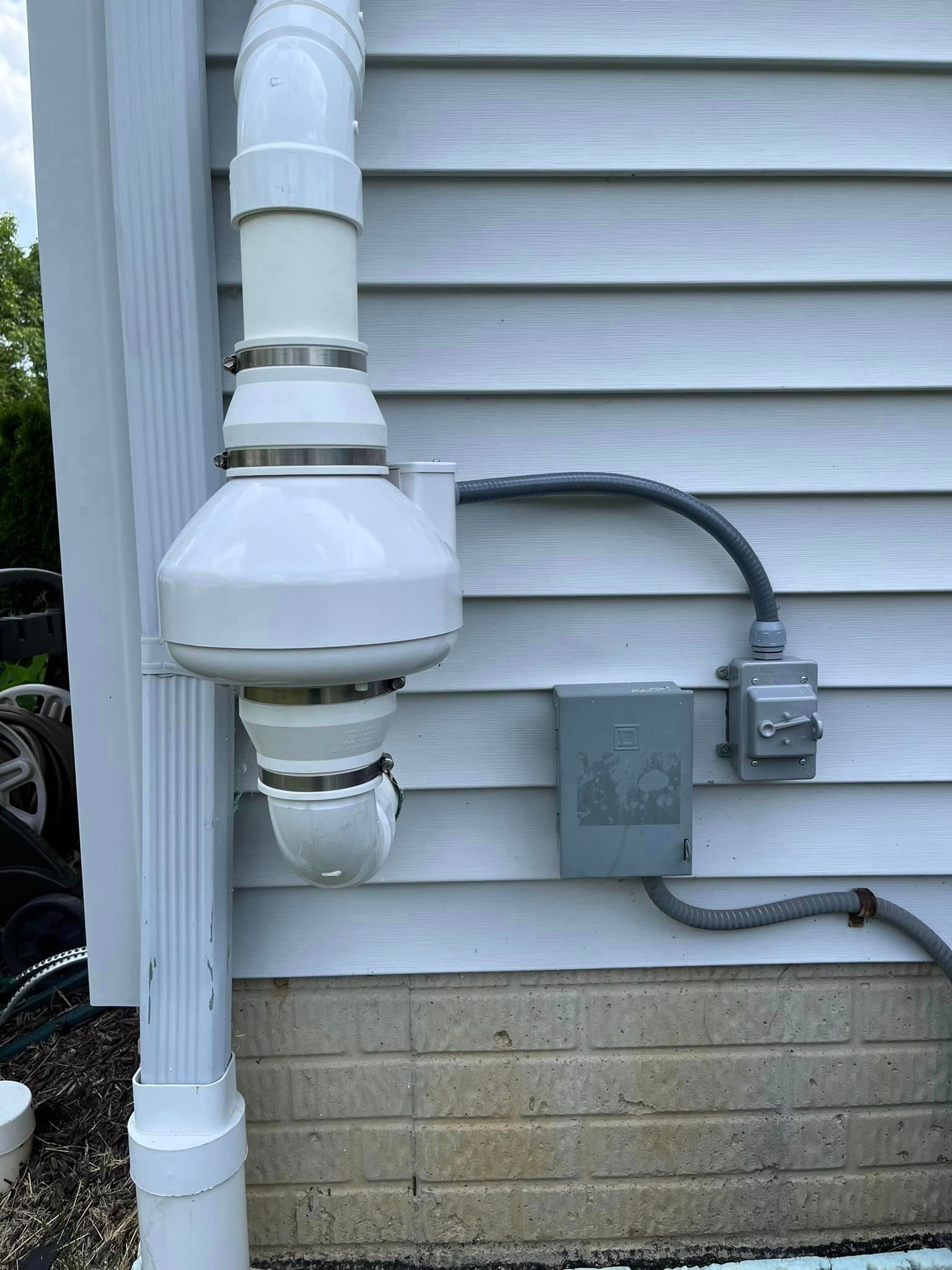 A white pipe is attached to the side of a house.
