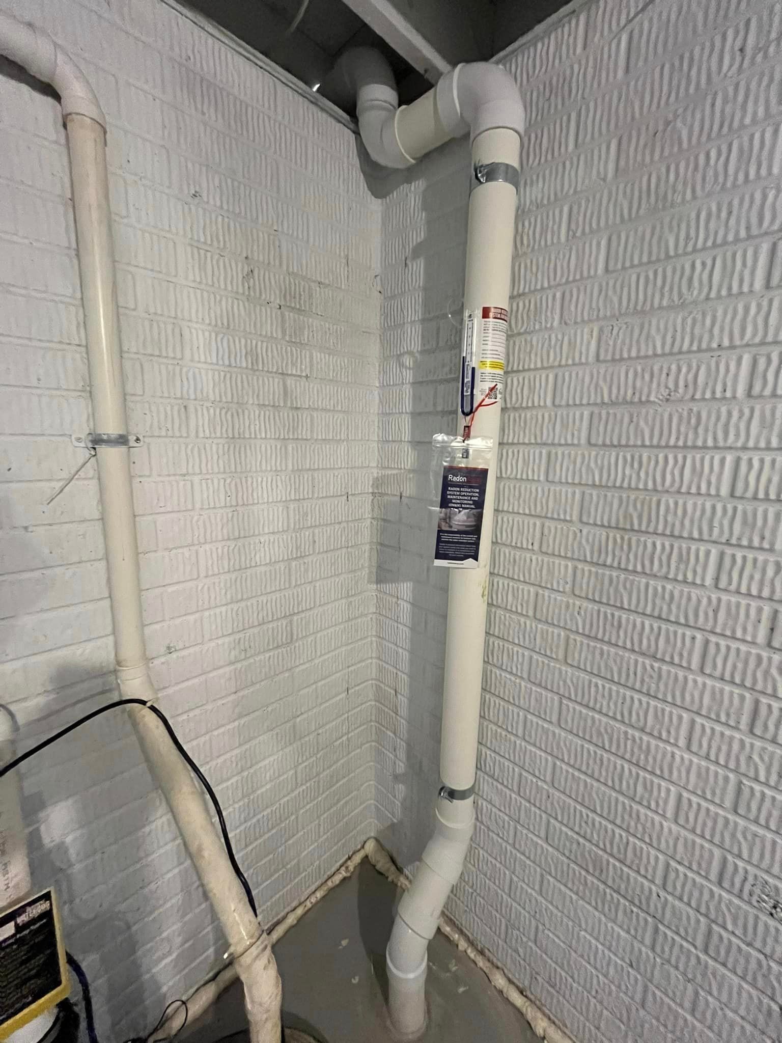 A white pipe is hanging from the ceiling in a basement.