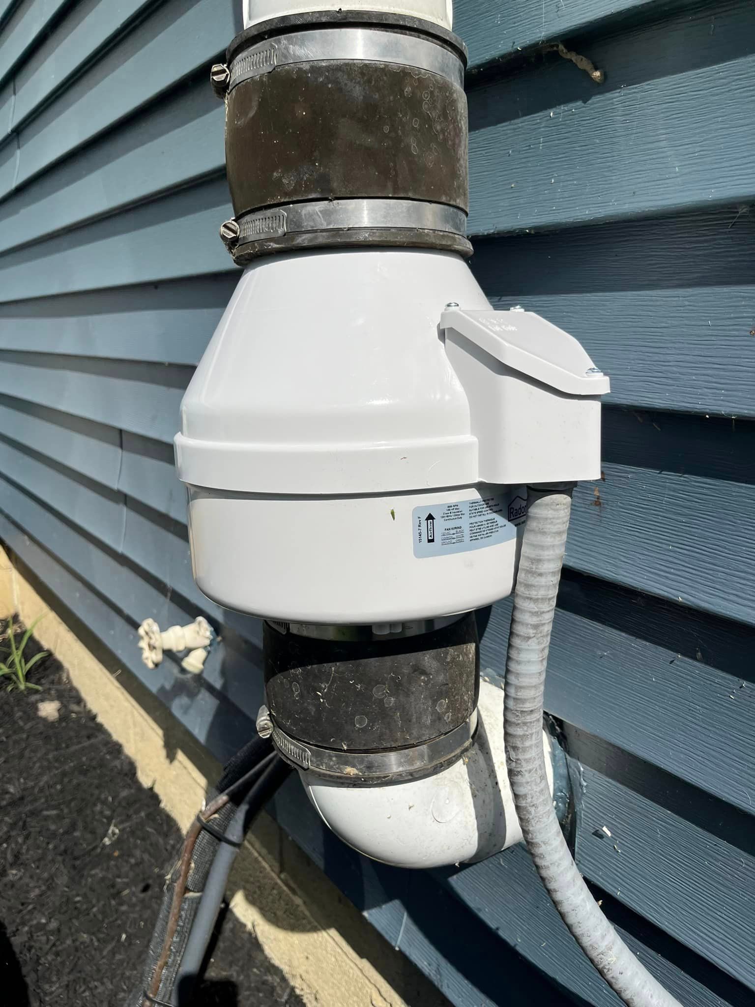 A white pipe is attached to the side of a building.