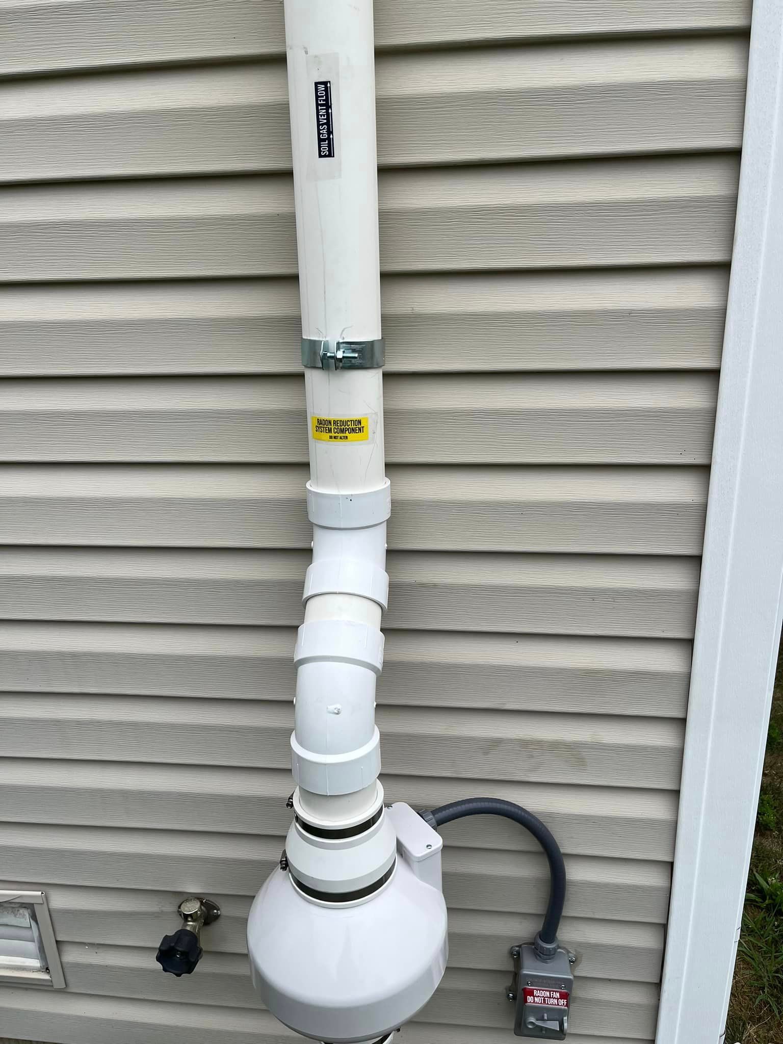 A white pipe is attached to the side of a house.