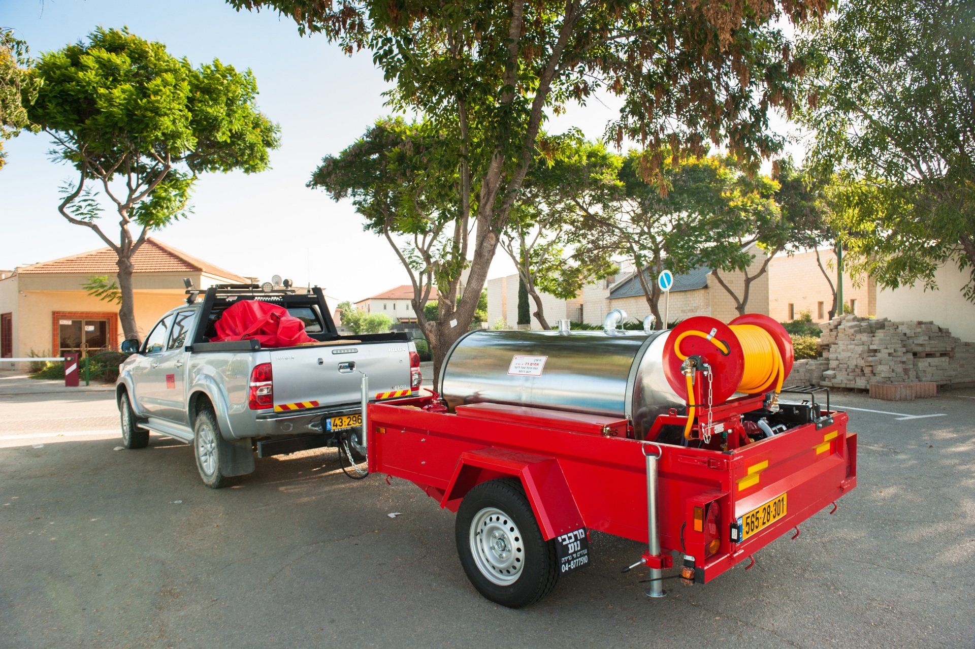 A truck is pulling a red trailer with a hose attached to it.