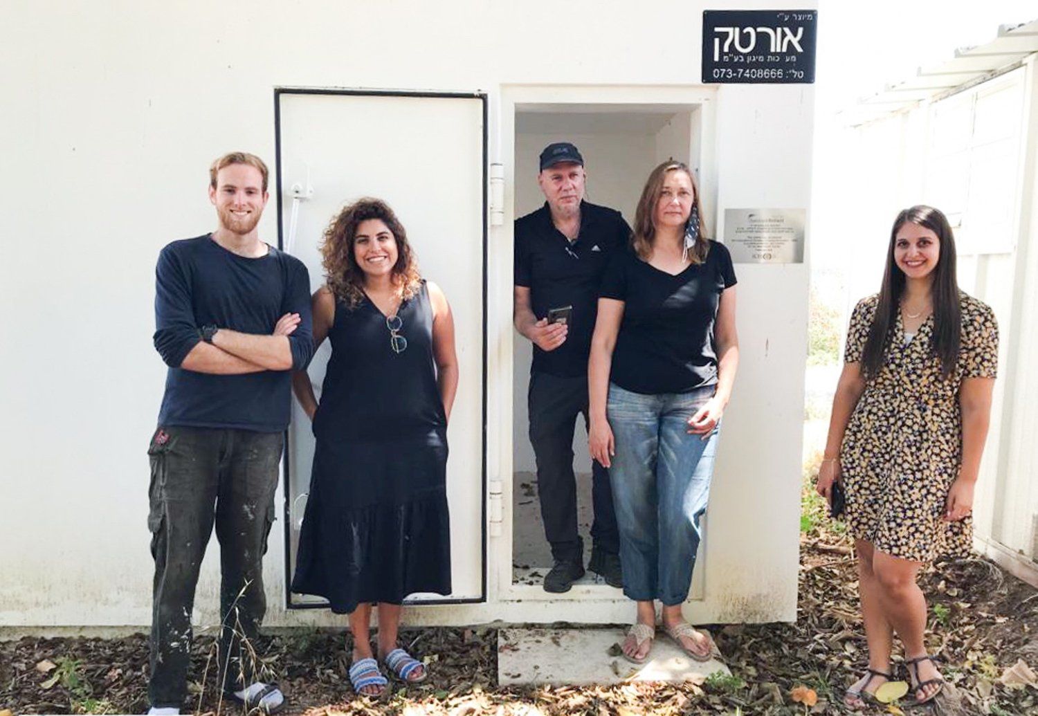 A group of people are standing in front of a white building.