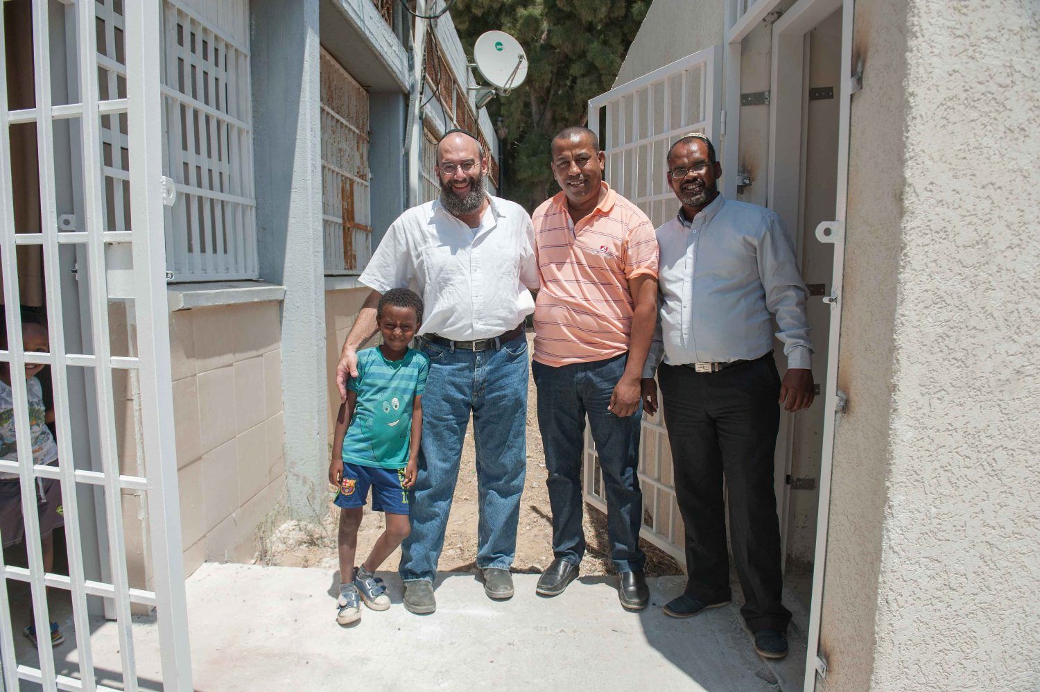 A group of men and a child are posing for a picture in front of a building.
