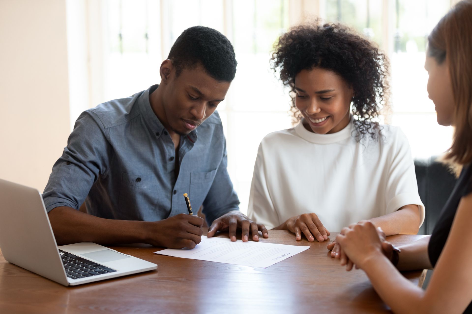 A man and a woman are sitting at a table signing a document.