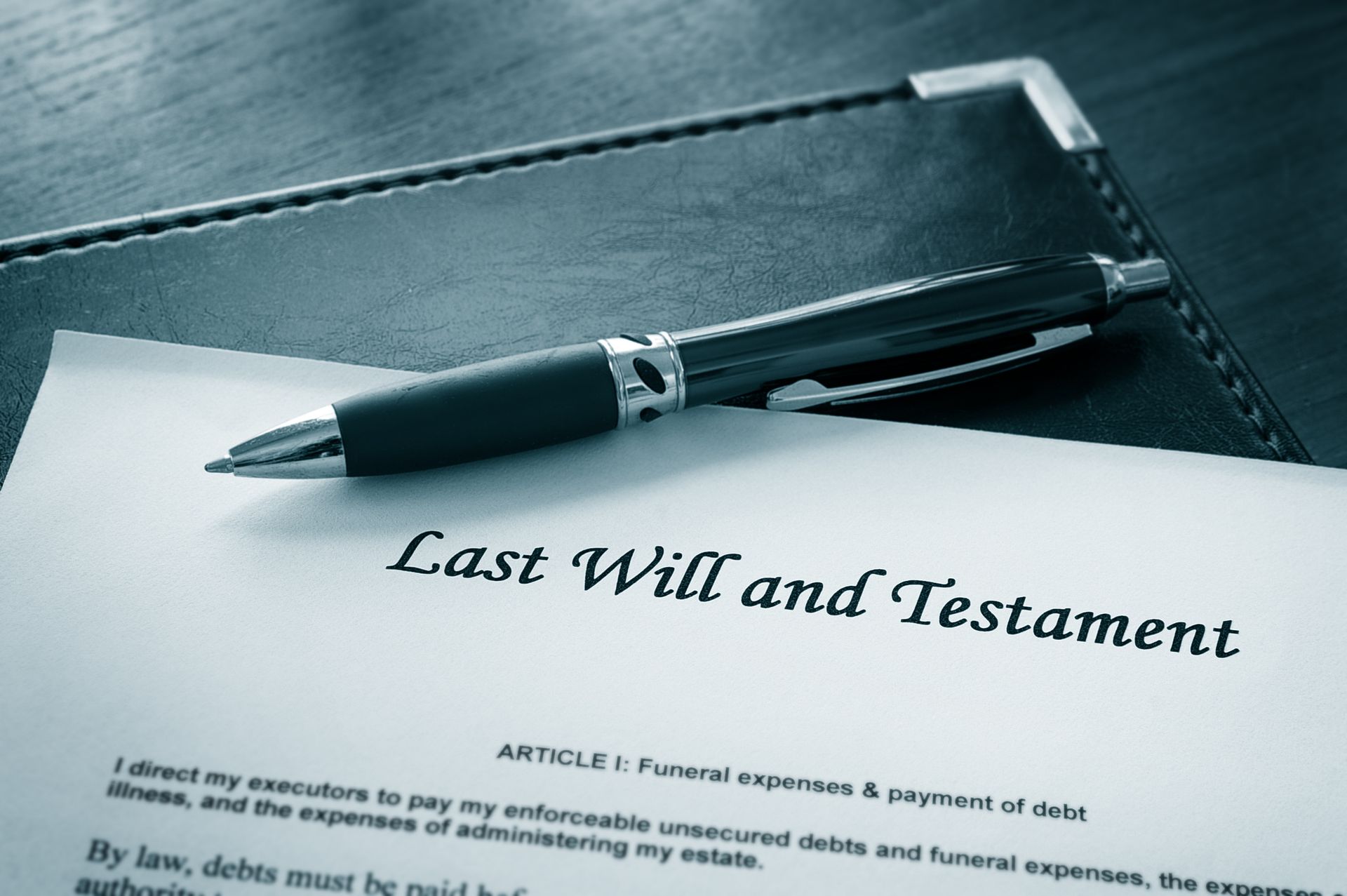 A pen is sitting on top of a last will and testament.