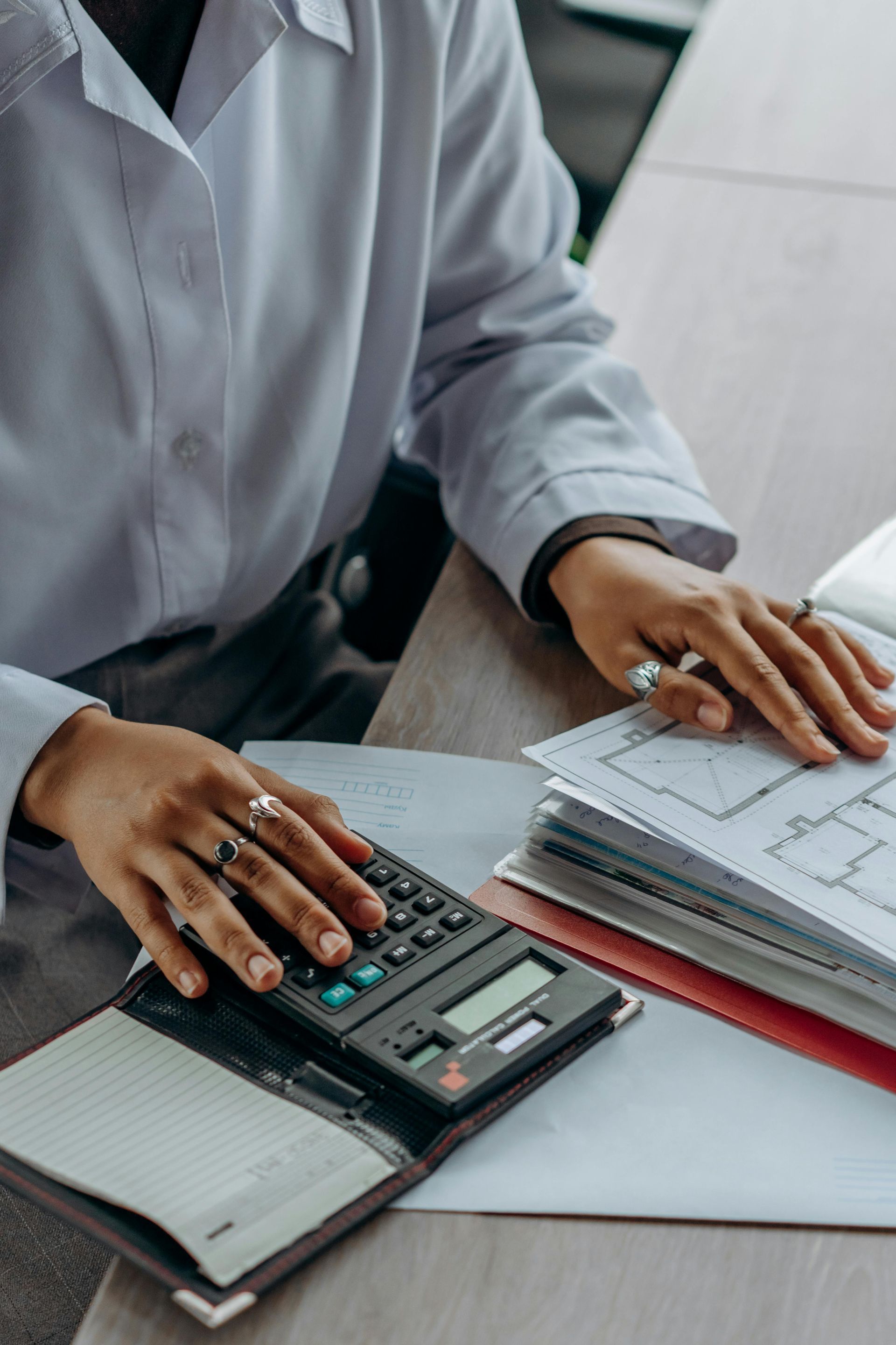 A woman is sitting at a desk using a calculator.