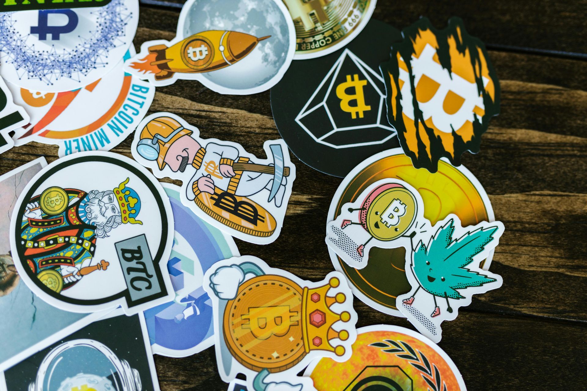 A bunch of stickers on a wooden table including one that says btc
