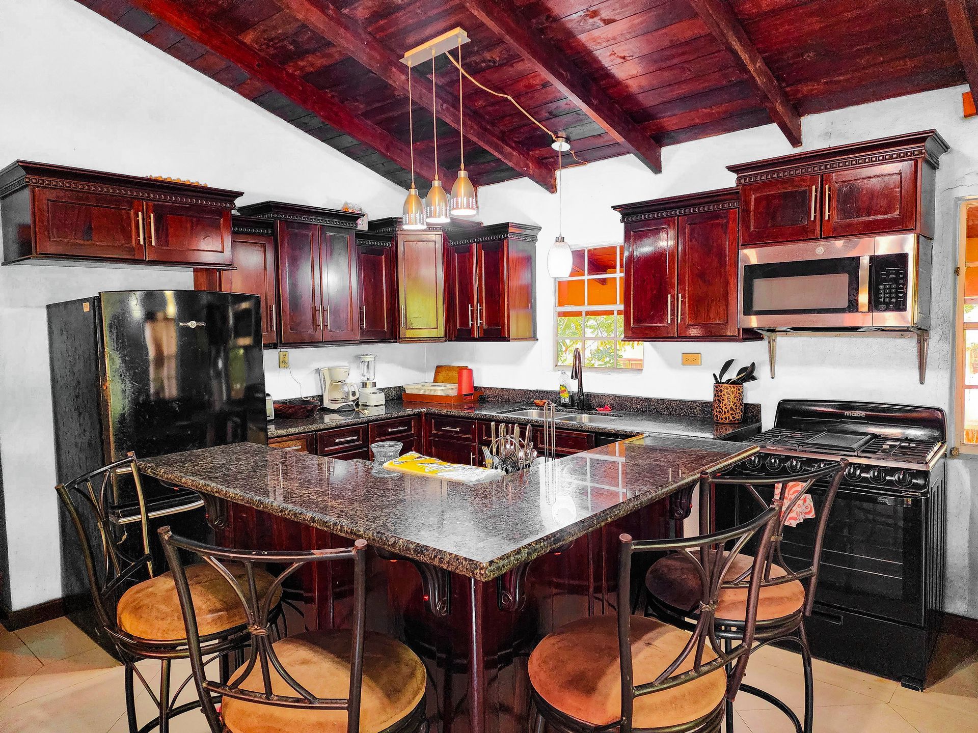 A kitchen with wooden cabinets and a granite counter top, shared Kitchen at Caribbean Shores B&B, Hopkins Belize 