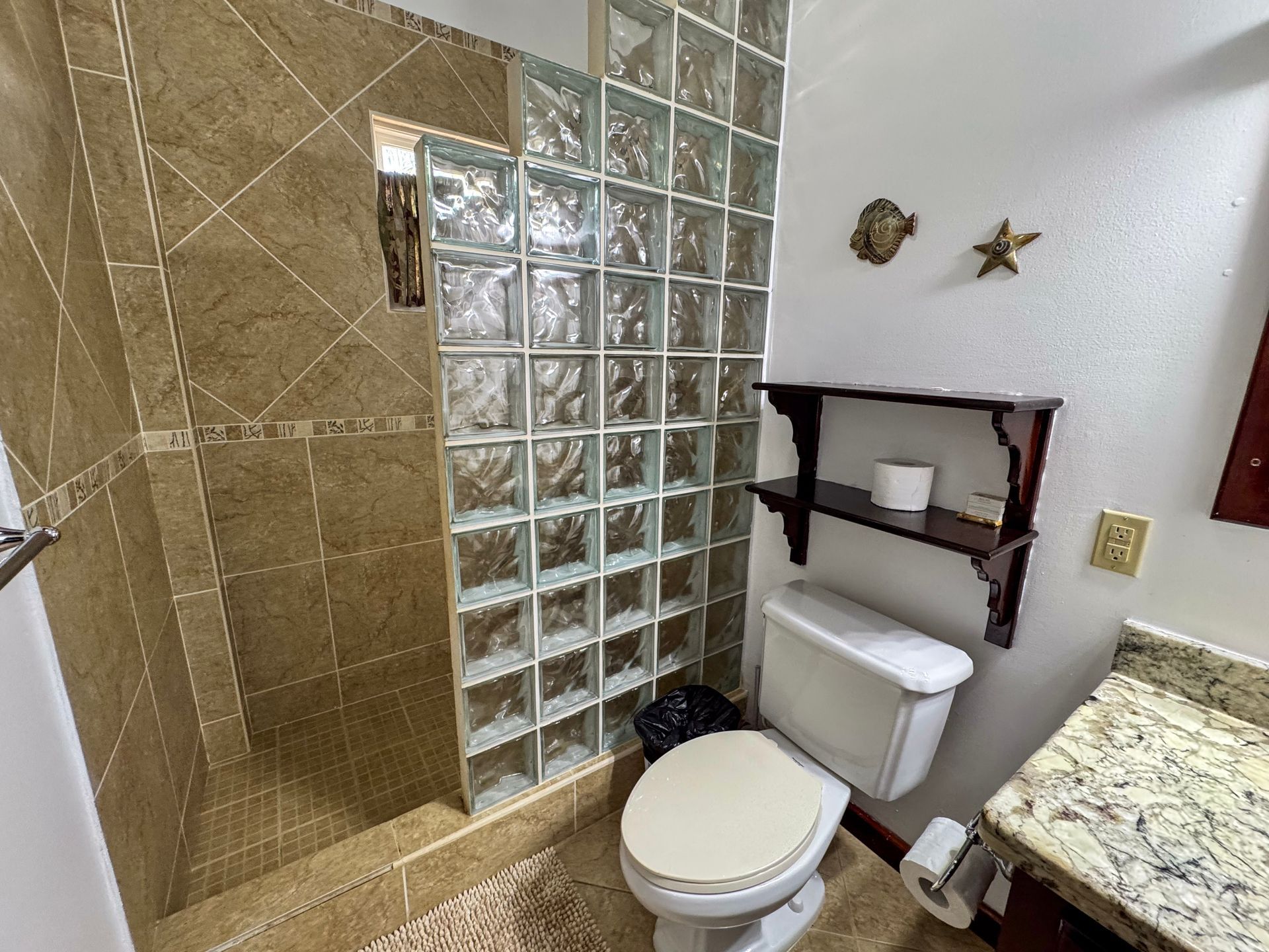 A bathroom with a toilet , sink and shower.