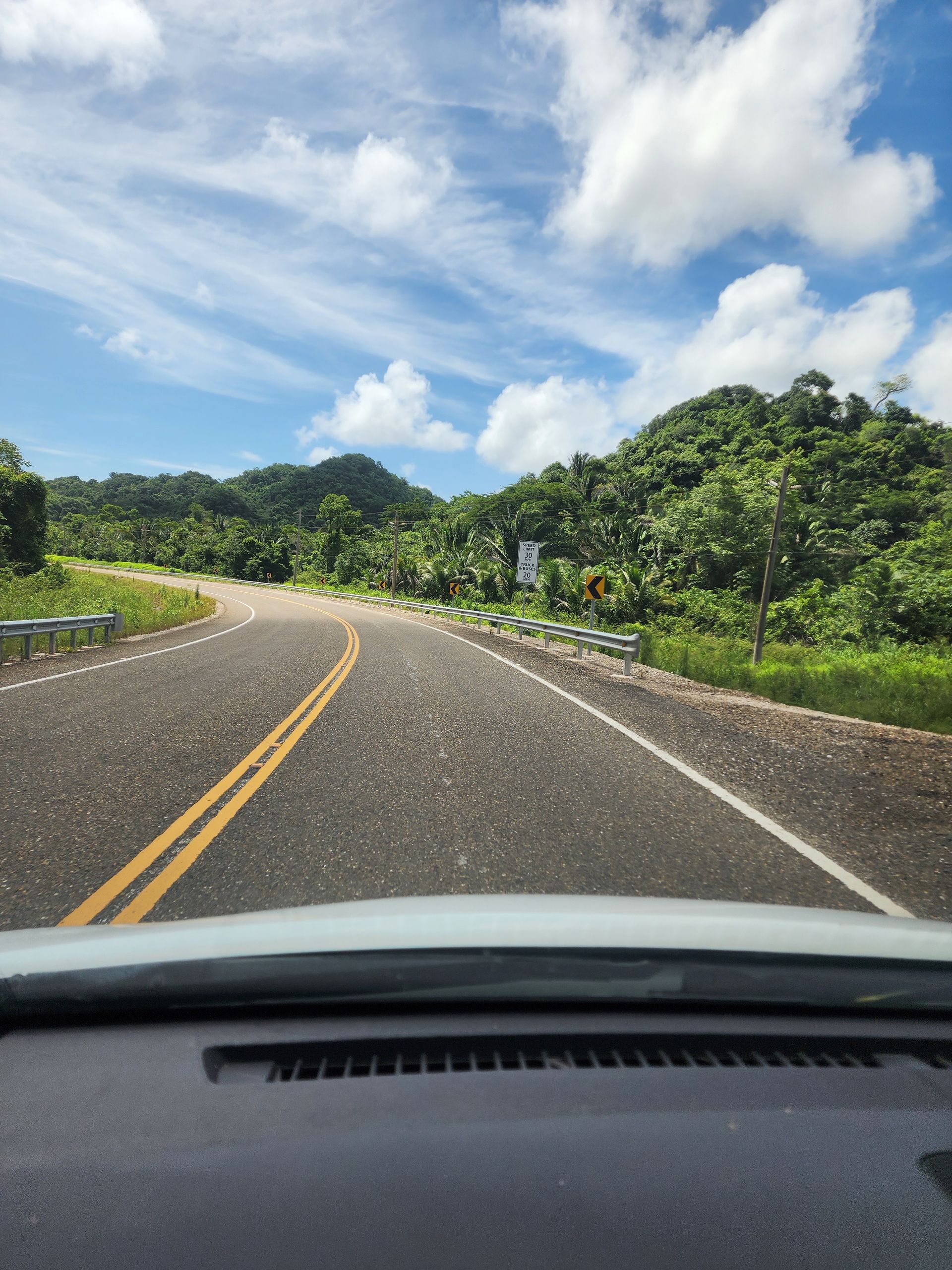 A car is driving down the Hummingbird Highway in Hopkins Village Belize 