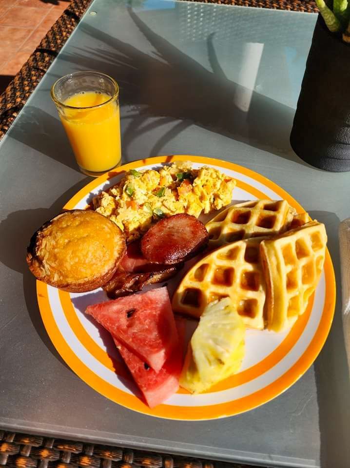 A plate of food on a table with a glass of orange juice, delicious breakfast in Hopkins Village Belize 