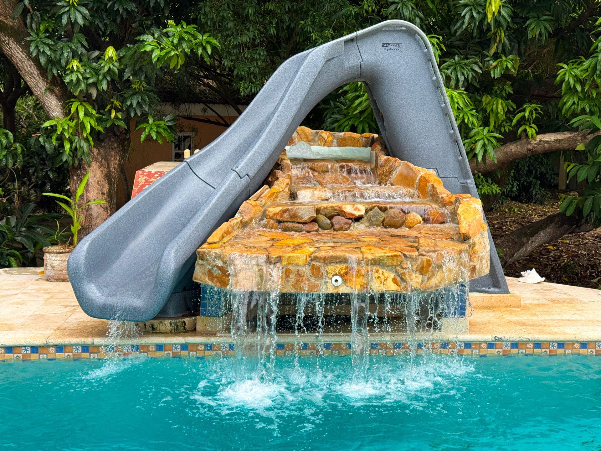 A pool with a slide and a waterfall in it.