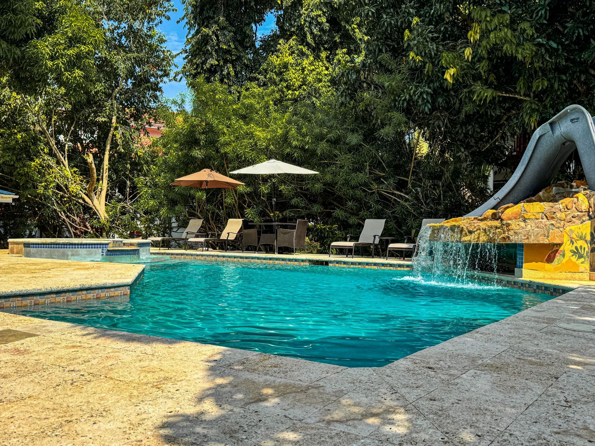 A large swimming pool with a slide and umbrellas