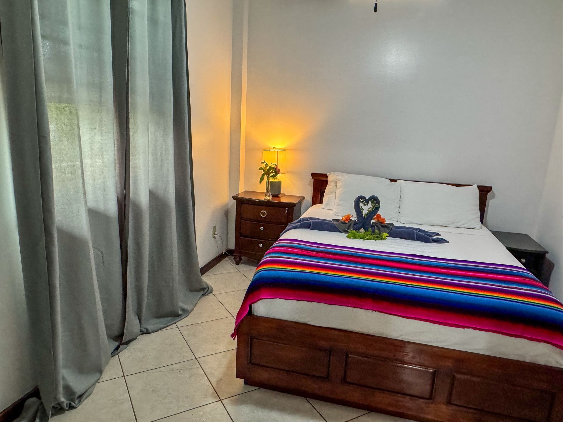 A bedroom with a bed , nightstand , and window.