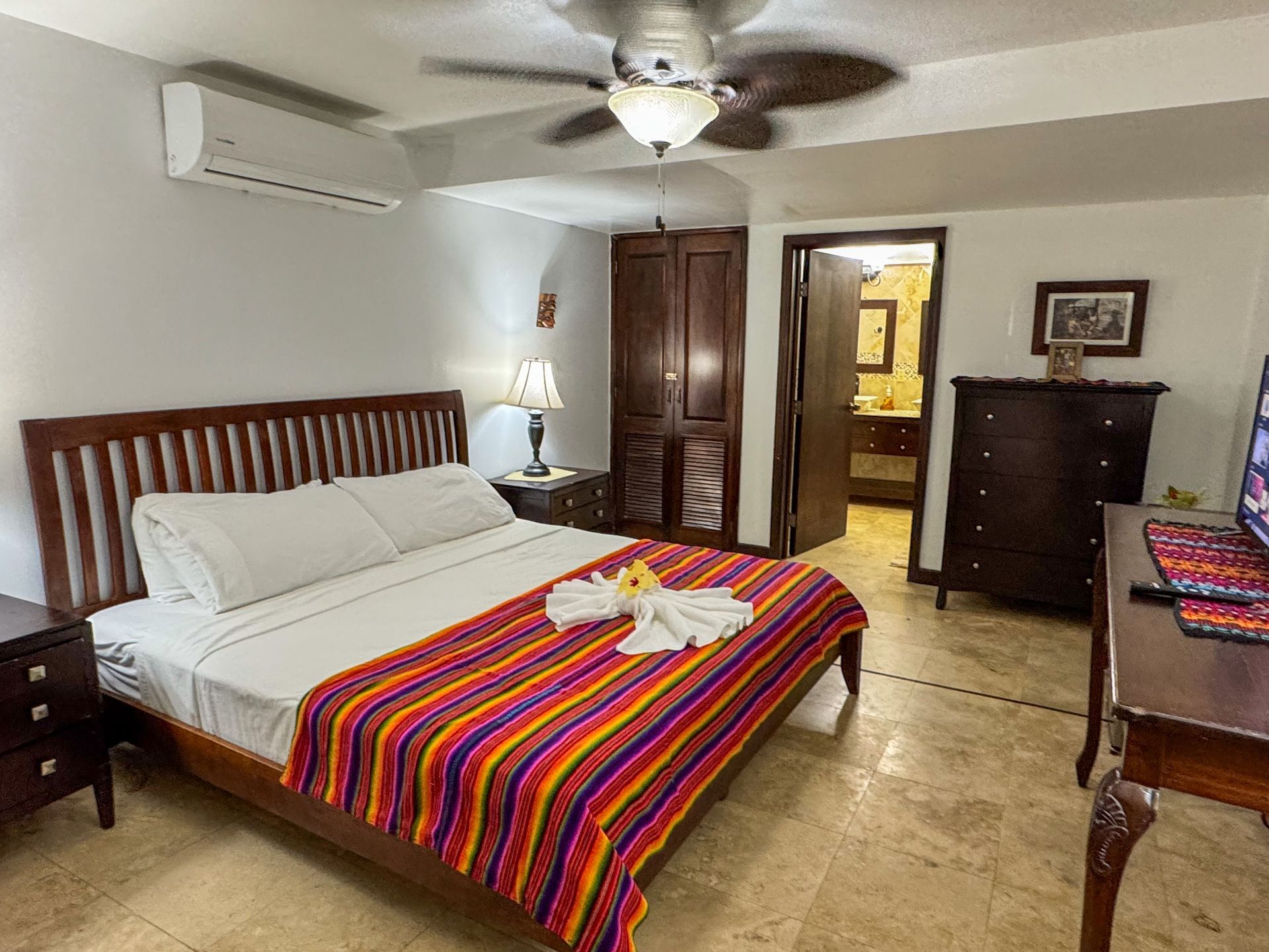 A hotel room with a king size bed and a ceiling fan, Belize Vacation getaway