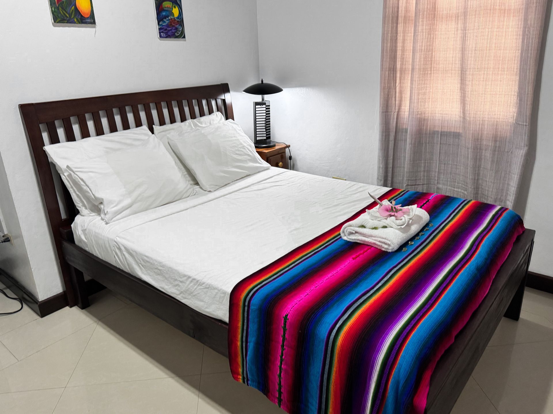 A double bed with a colorful blanket on it in a hotel room, solo traveler accommodation in Hopkins, Belize