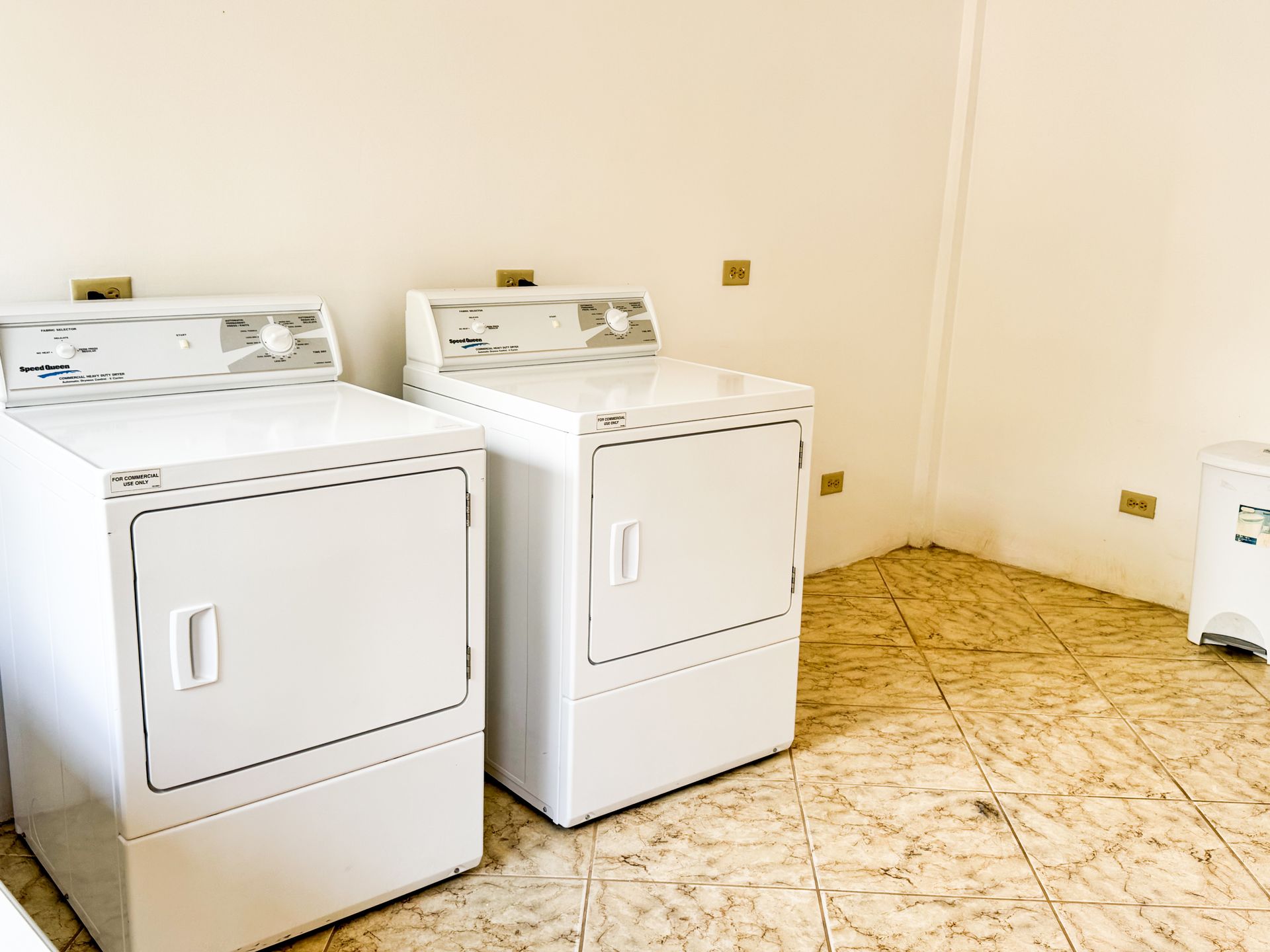 Two white washers and dryers are sitting next to each other in a laundry room.