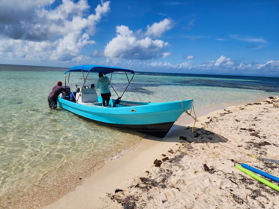 A blue boat is docked at South Water Caye, snorkeling tours in Hopkins Village, Belize