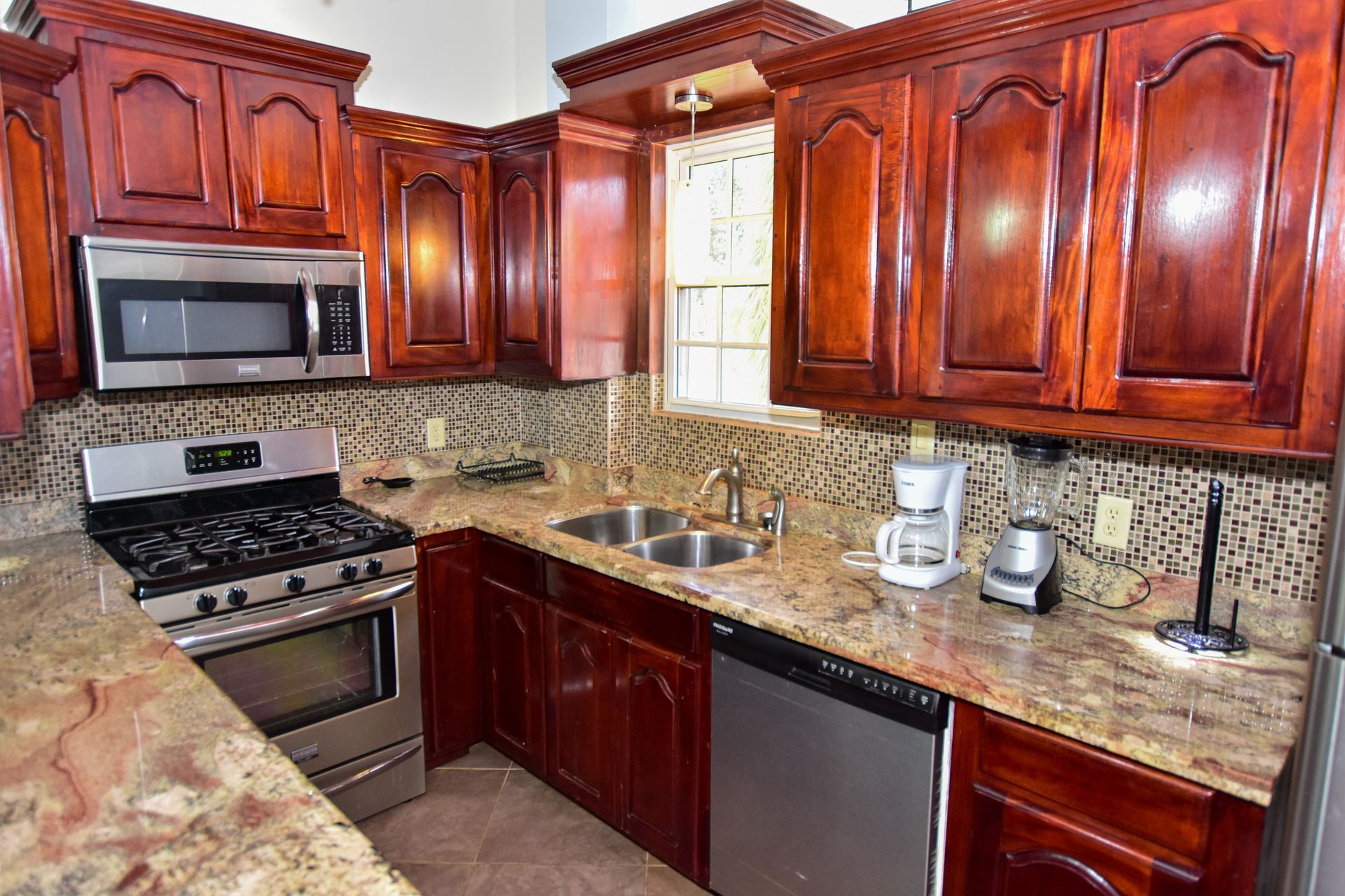 A kitchen with wooden cabinets , stainless steel appliances and granite counter tops.