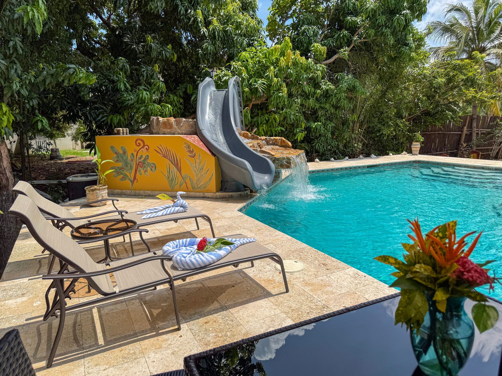 A swimming pool with a water slide and chairs around it