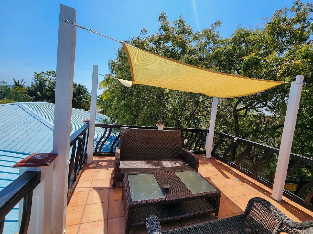 A rooftop with furniture and a yellow shade sail at Caribbean Shores B&B , Hopkins Village