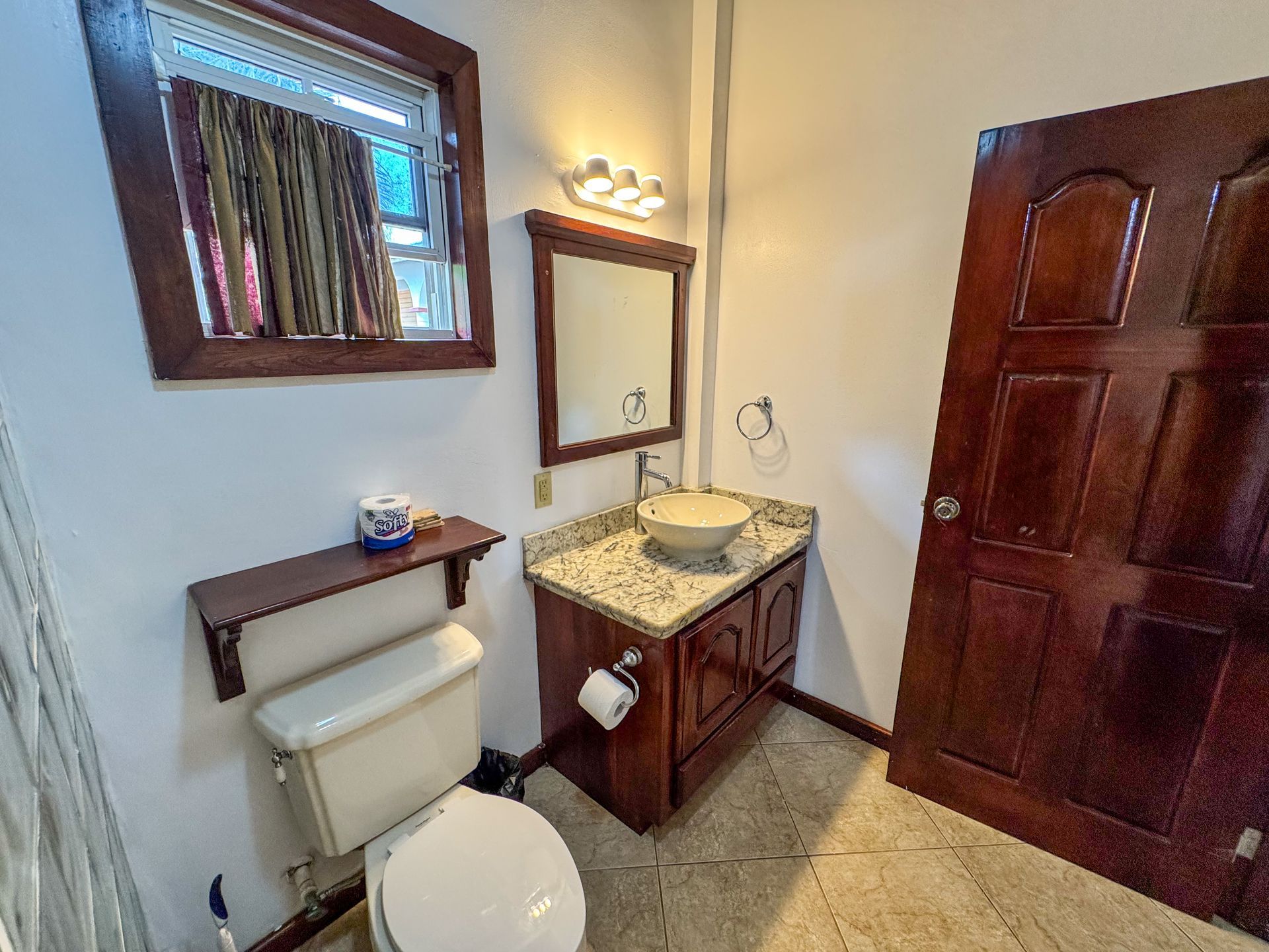 A bathroom with a toilet , sink and mirror.