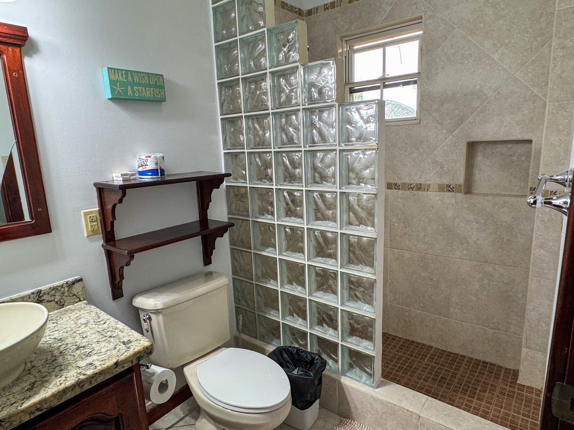 A bathroom with a toilet , sink , mirror and walk in shower.