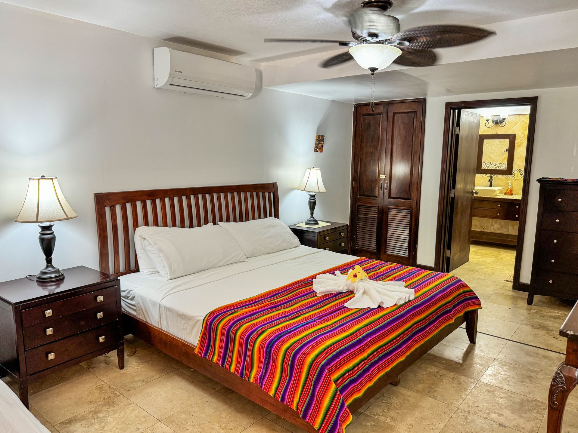A hotel room with a king size bed and a ceiling fan