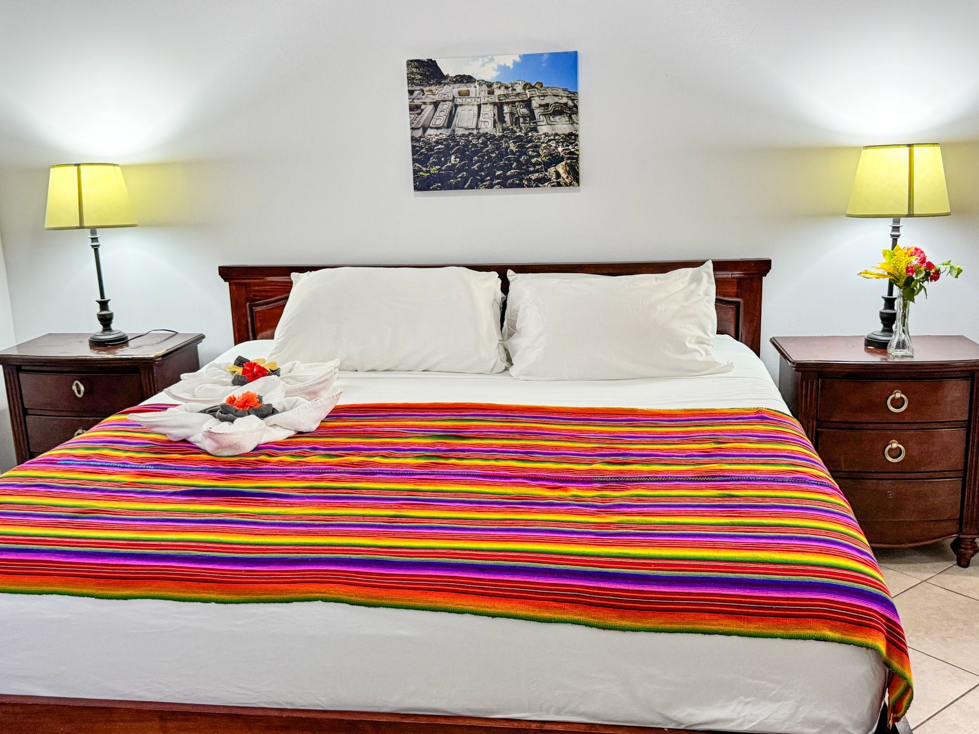 A hotel room with a bed , nightstands , lamps and a picture on the wall.