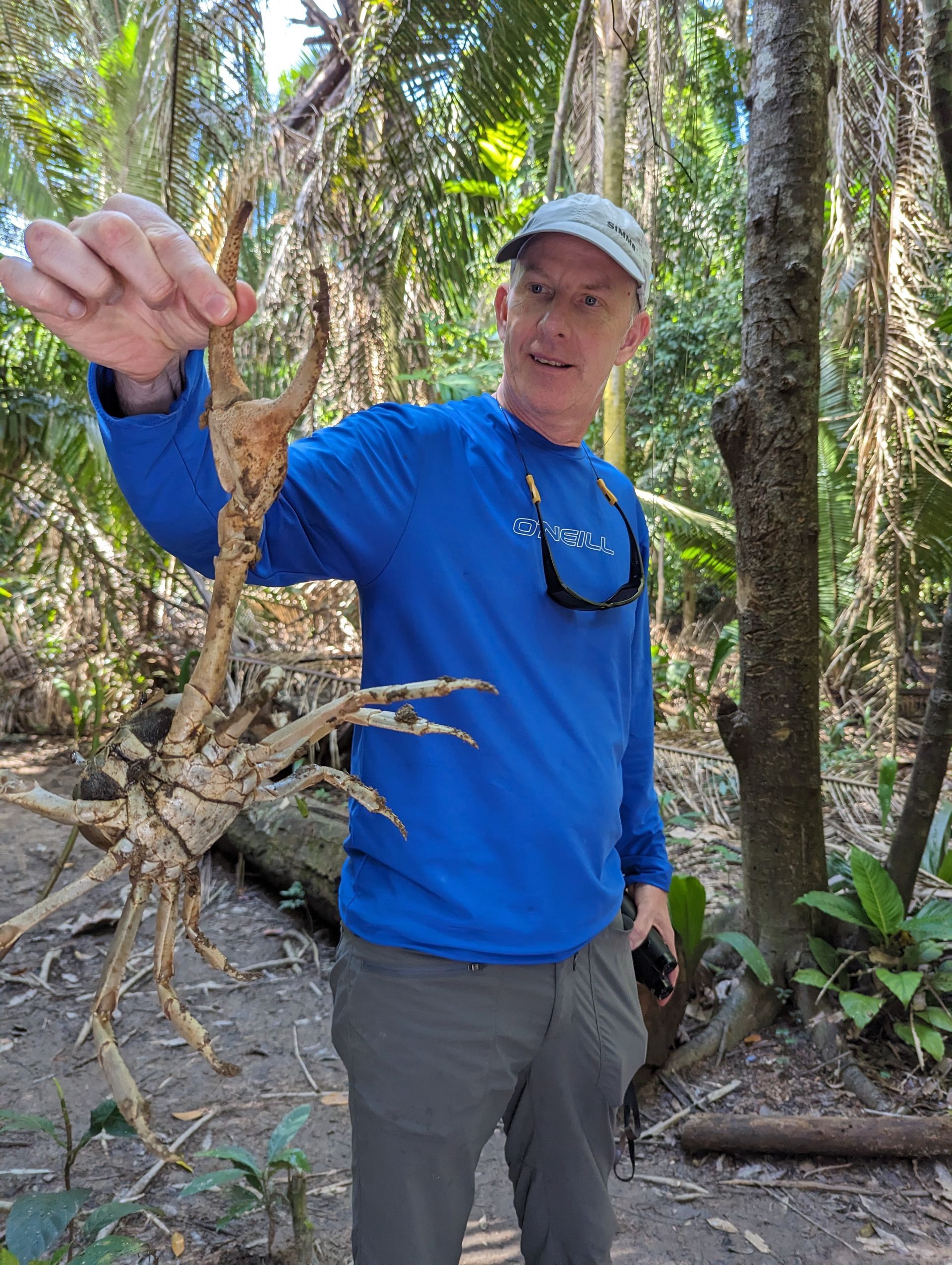 a man holding a crab exploring the jungle in Belize during the Monkey River Tour 