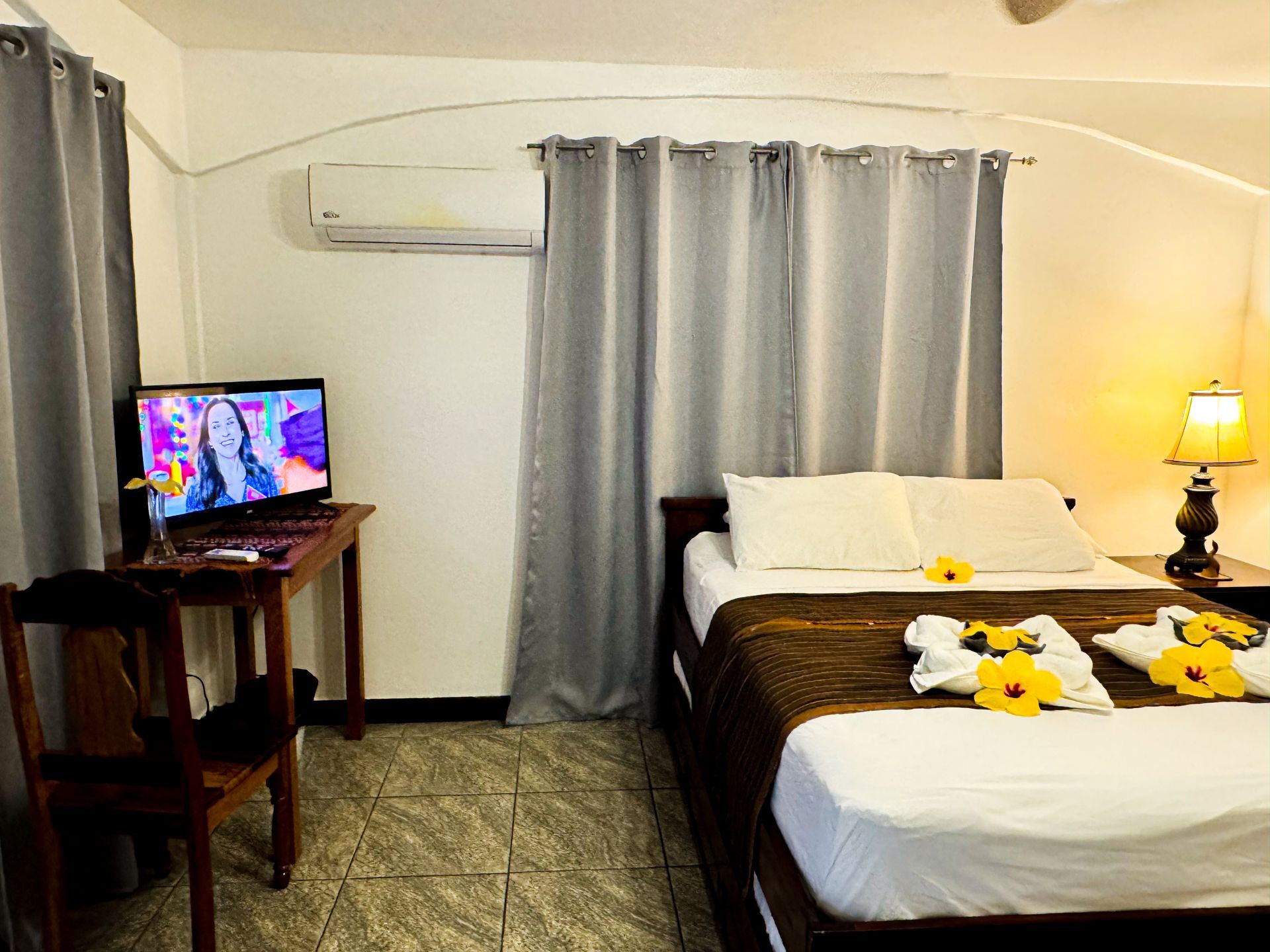 A hotel room with two beds , a desk and a television, comfortable accommodation in Hopkins Belize