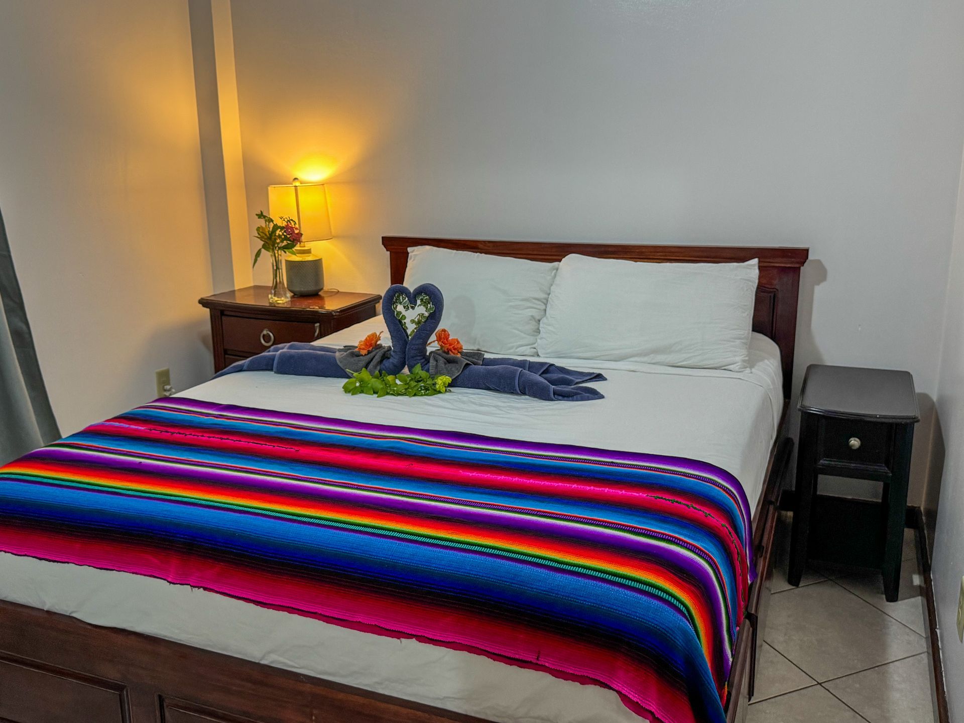 A bed with a colorful blanket and towels on it in a hotel room, best place to stay in Hopkins Village, belize