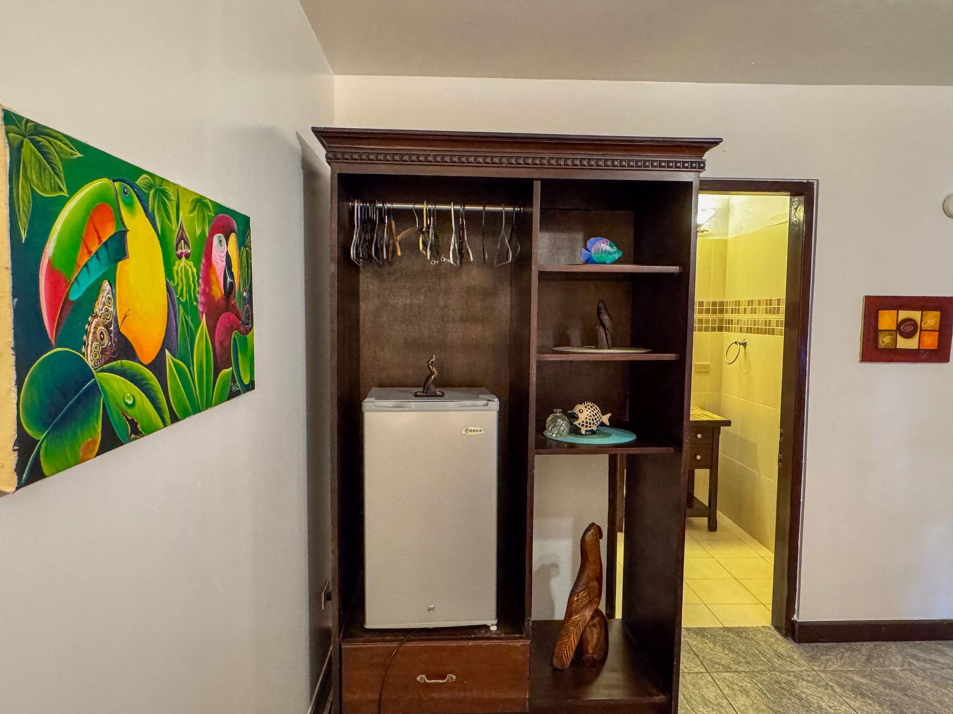 A room with a refrigerator and a painting on the wall.