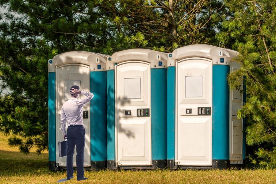 Man Standing in Front of Portable Restroom