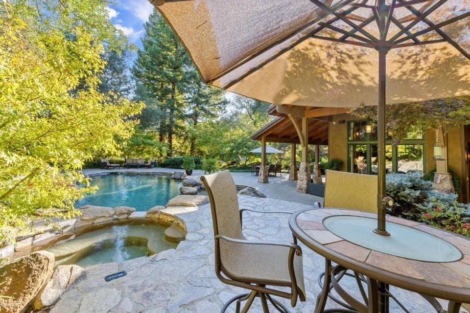 A full bathroom, outdoor kitchen and fireplace are near the pool.