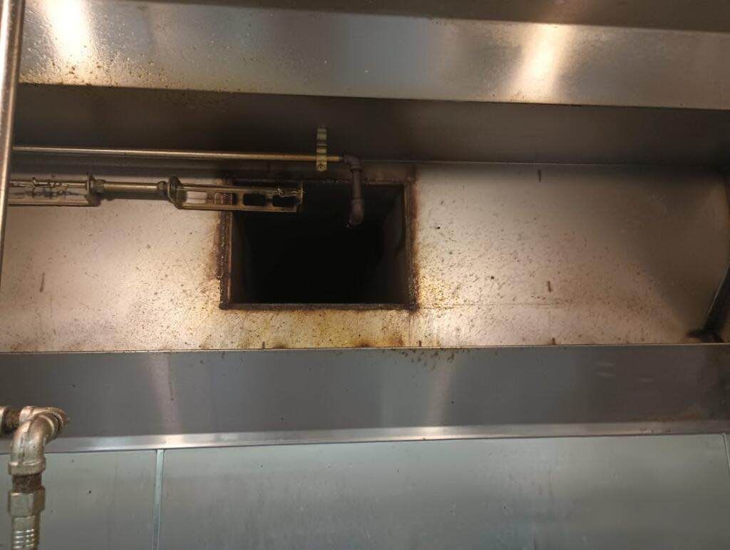 A stainless steel hood with a hole in it in a kitchen.