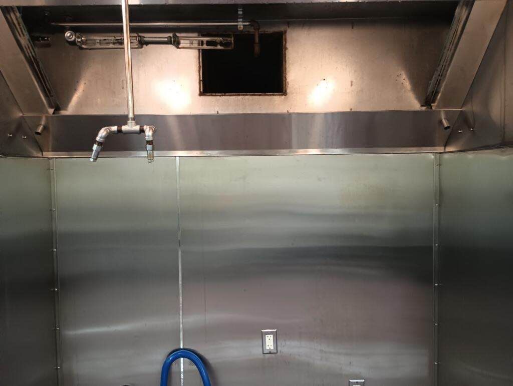 A stainless steel wall with a hose attached to it.
