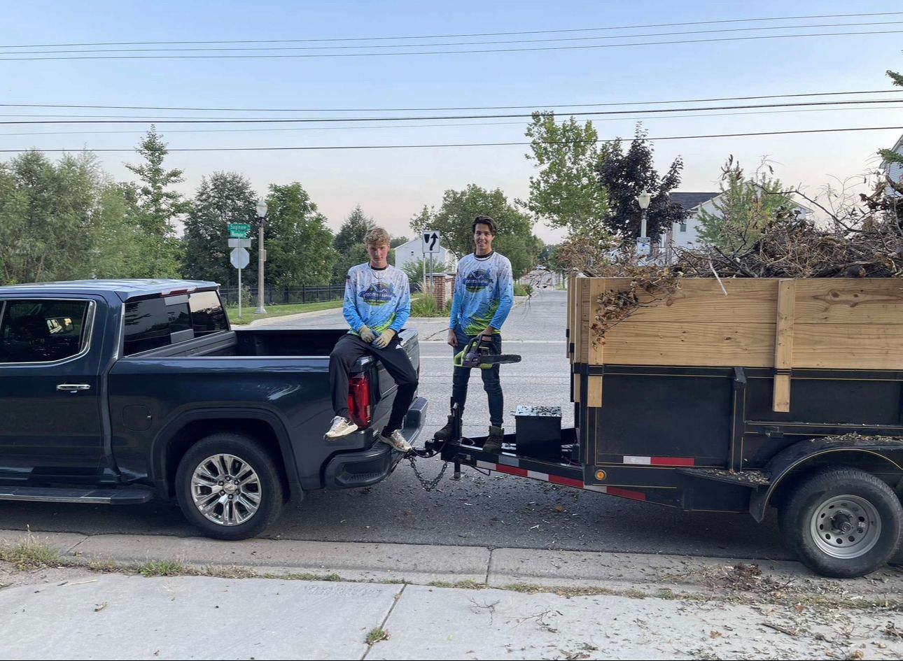 Two men are standing next to a truck with a trailer attached to it.