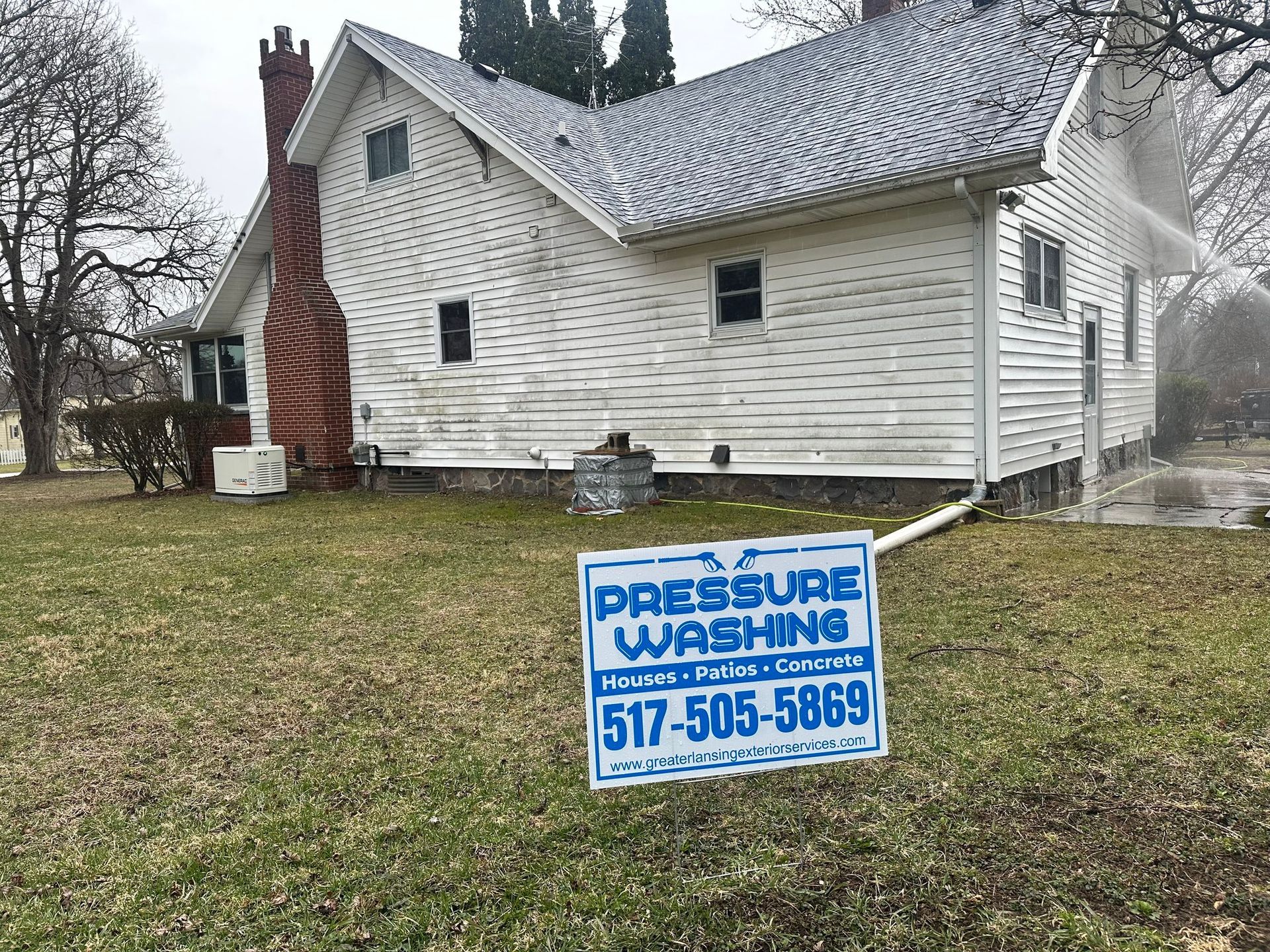A white house with a pressure washing sign in front of it.