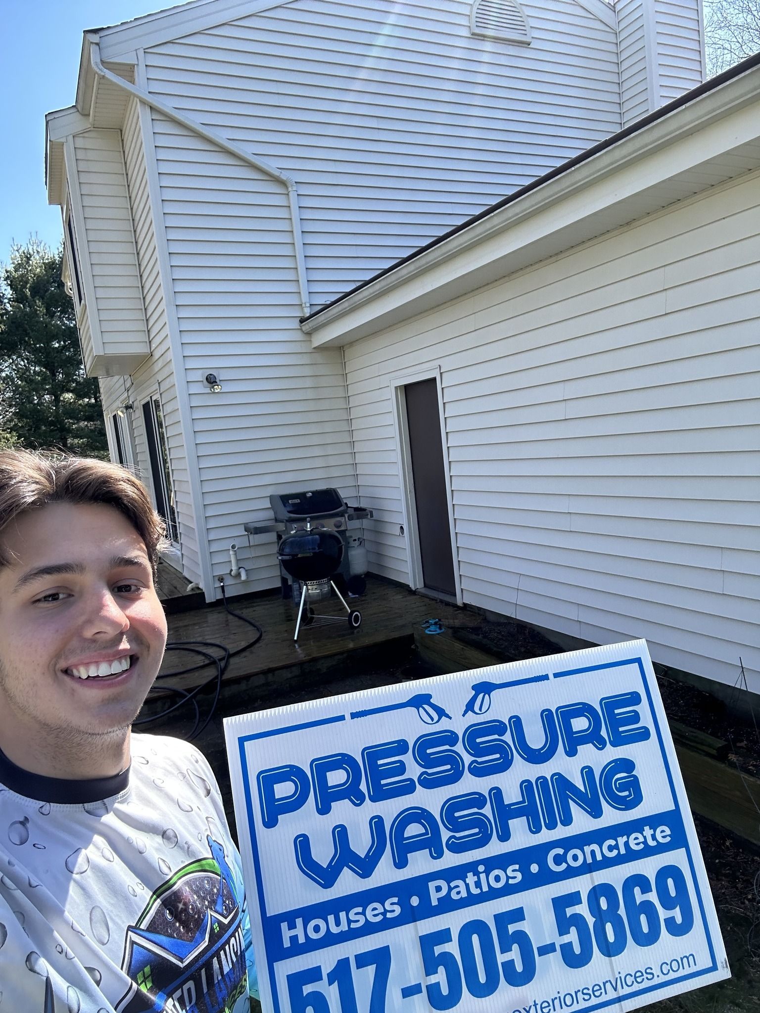 A young man is holding a sign in front of a white house.