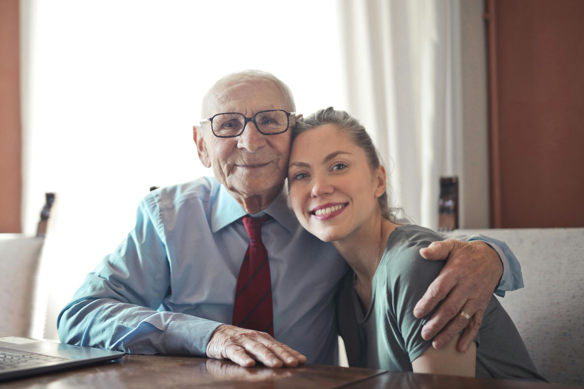 An elderly man and a young woman are posing for a picture.