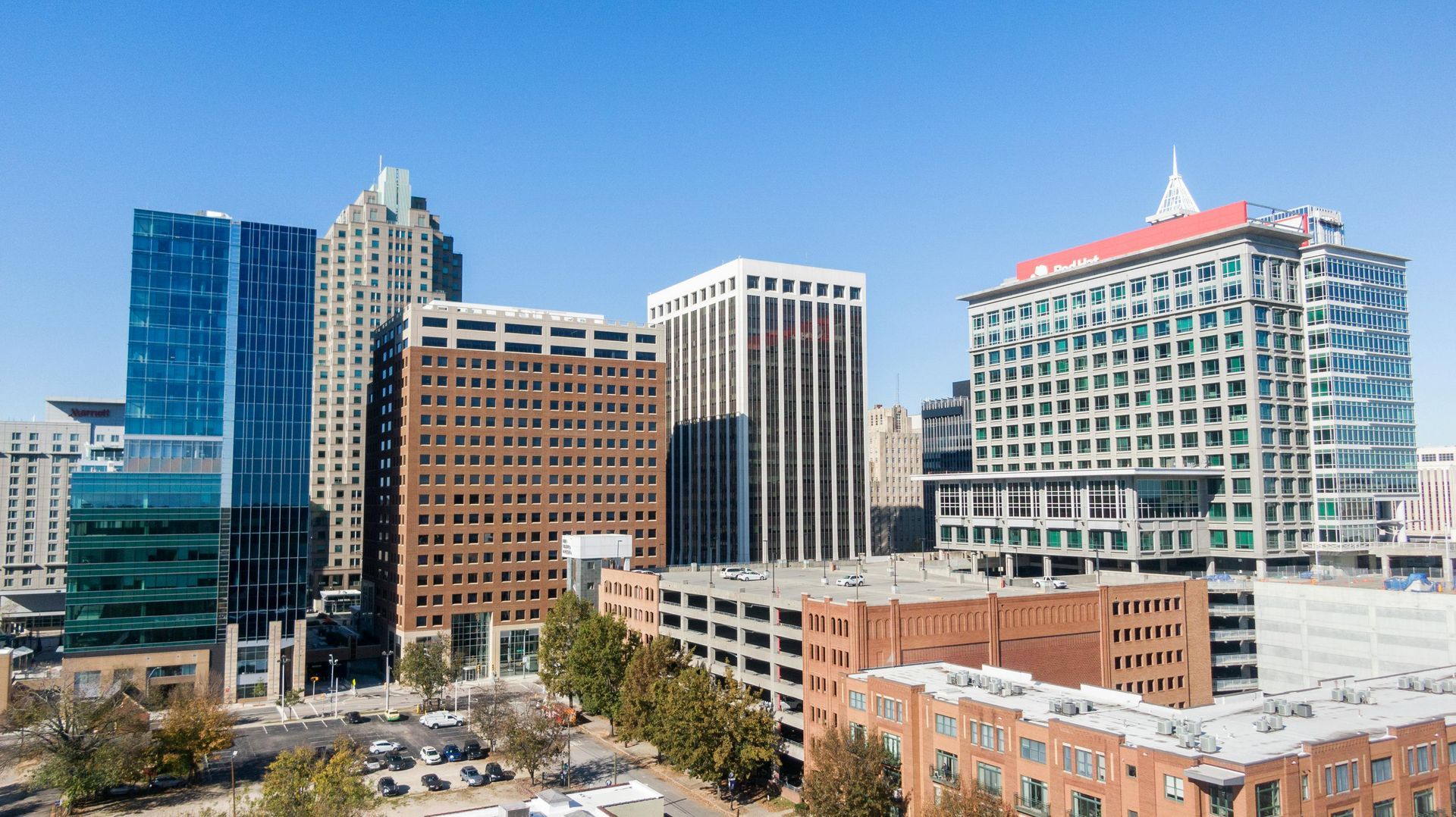 An aerial view of a city skyline with lots of tall buildings and a parking garage.